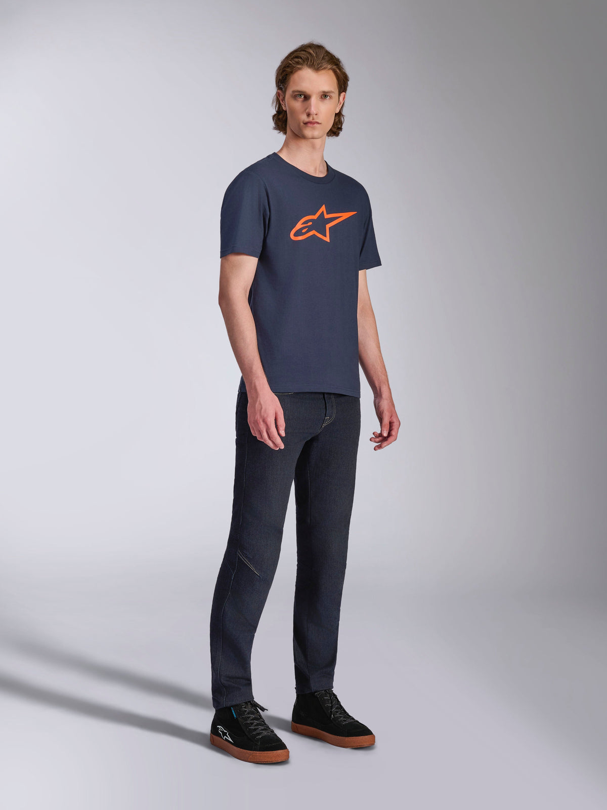 Alpinestars Ageless 2.0 CSF Tee, Short Sleeve T-Shirt, Navy Blue with Orange Star Logo, worn with dark denim jeans and black sneakers, casual motorsport-inspired streetwear