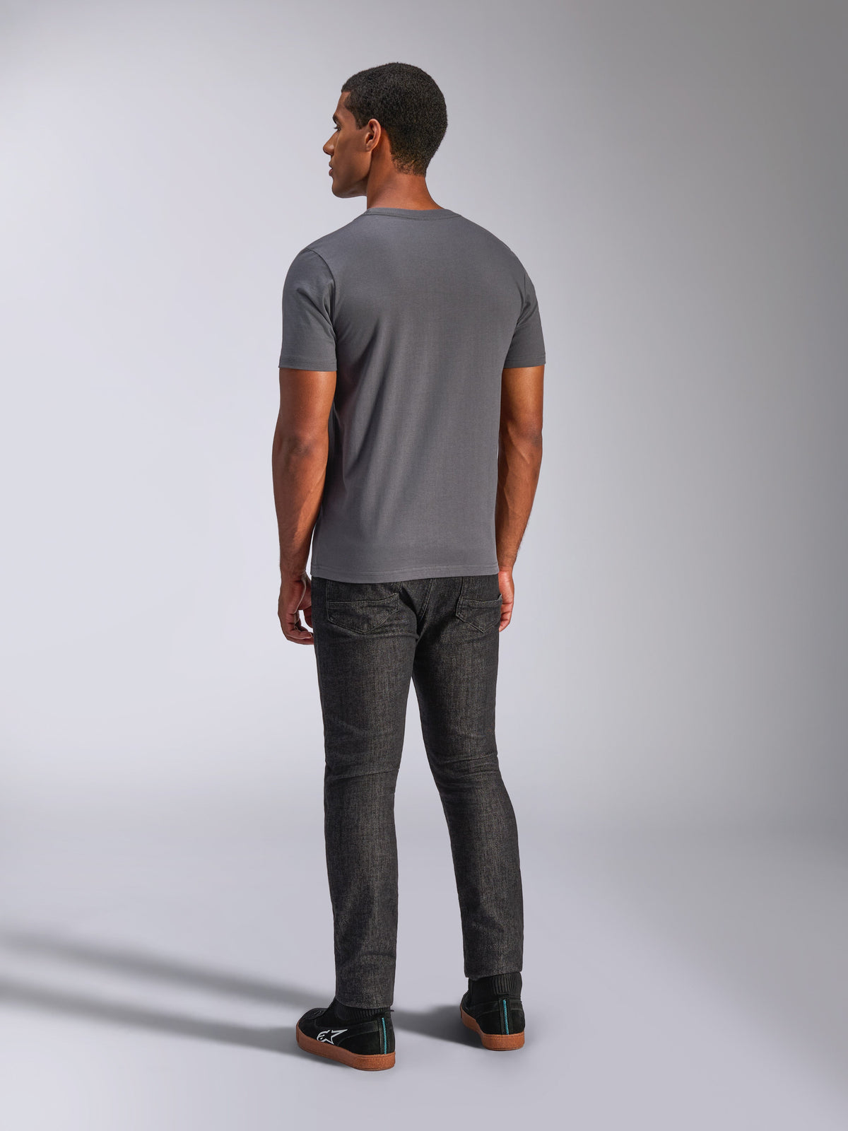 Alpinestars Always 2.0 CSF Tee, Kurzarm-T-Shirt, Anthrazitgrau, Rückansicht am Modell, kombiniert mit dunkler Denim-Hose und schwarzen Sneakern, lässige, vom Motorsport inspirierte Streetwear