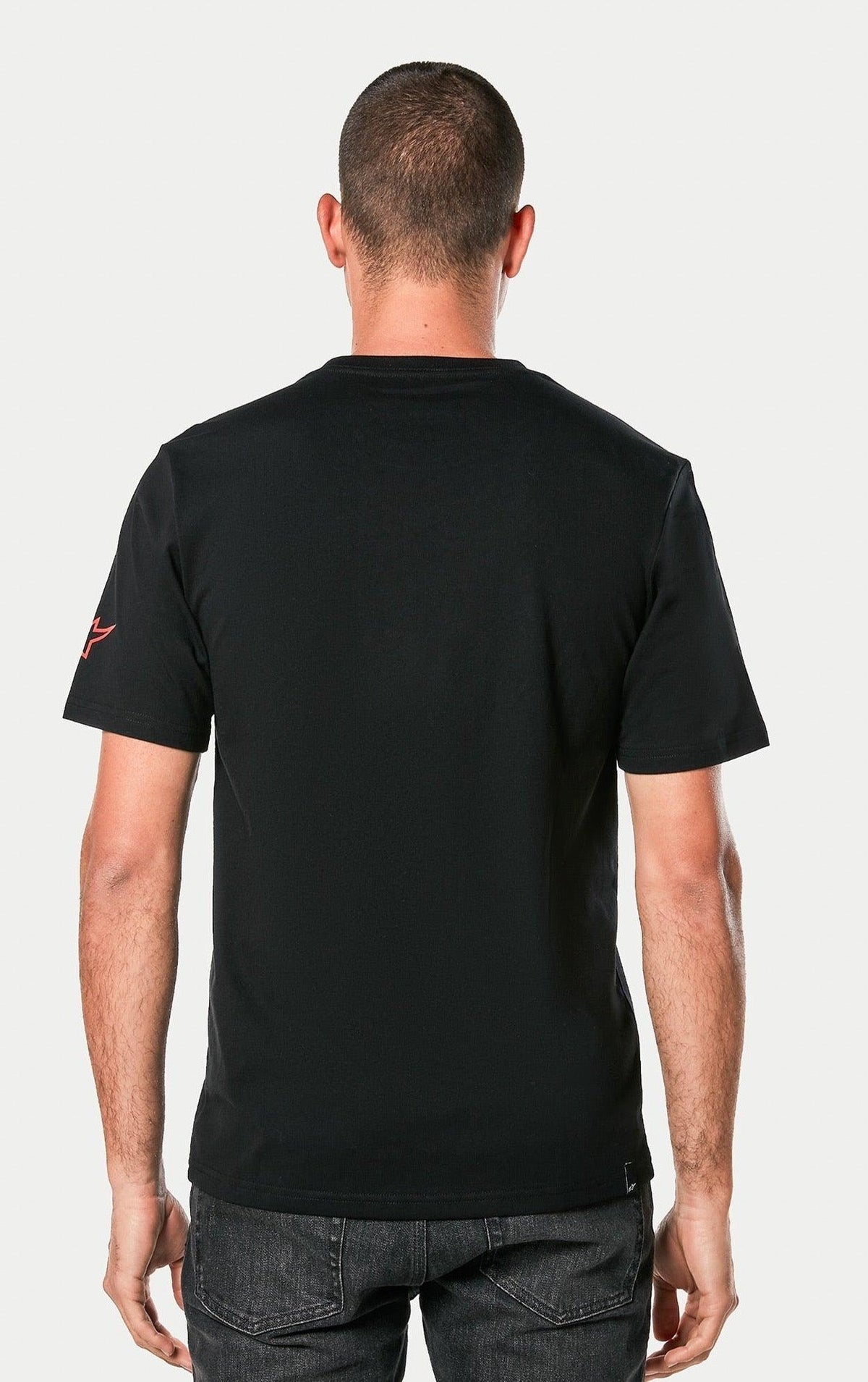 Alpinestars Linear Wordmark 2.0 CSF Tee, Schwarz, Rückansicht einer Person im kurzärmeligen T-Shirt, mit rotem Ageless-Logo am Ärmel, lässige Motorsport-Streetwear