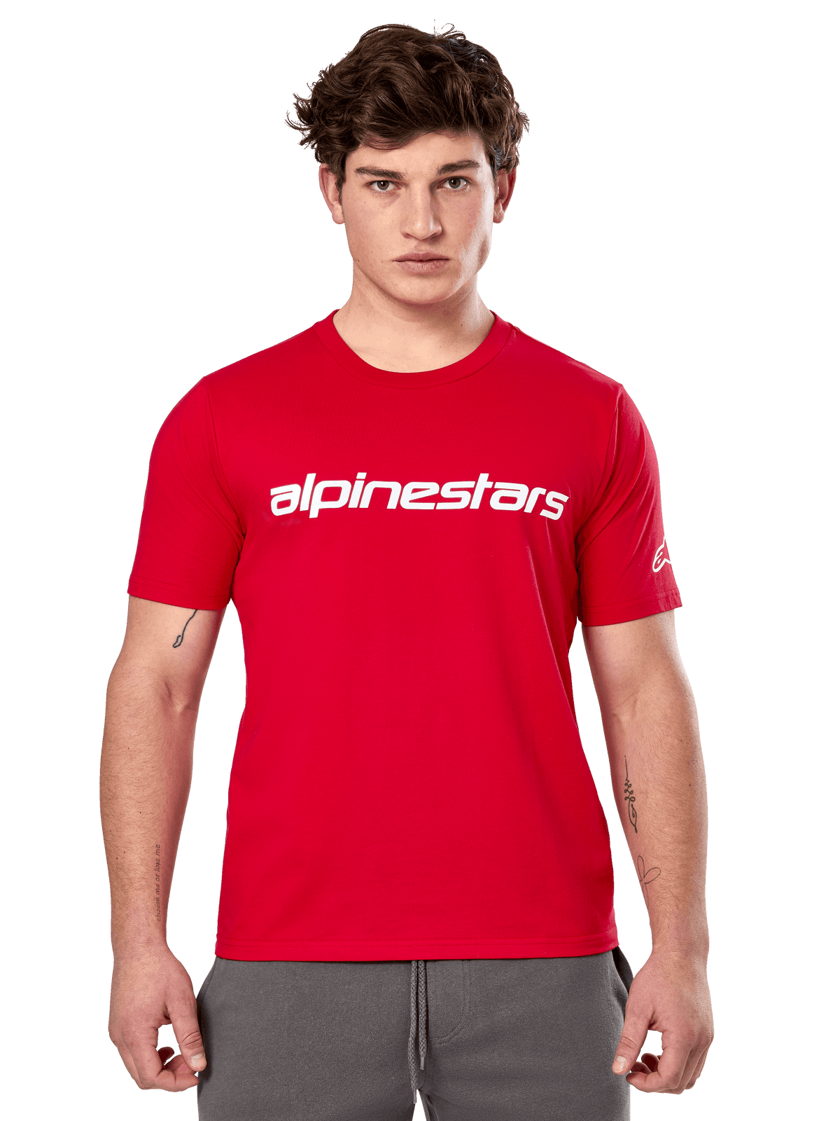Alpinestars Linear Wordmark 2.0 CSF Tee, Kurzarm-T-Shirt, Rot, weißer linearer Schriftzug auf der Brust und Ageless-Logo am Ärmel, getragen von einem männlichen Model mit grauer Jogginghose, lässige, vom Motorsport inspirierte Streetwear