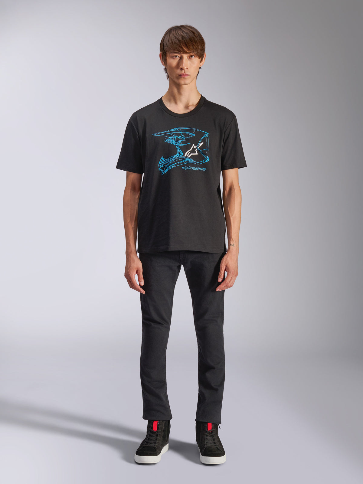 Alpinestars CSF Tee, Short Sleeve T-Shirt, Black, Blue Motocross Helmet Graphic with White Logo, worn by a model with black pants and black sneakers, casual motorsport-inspired streetwear