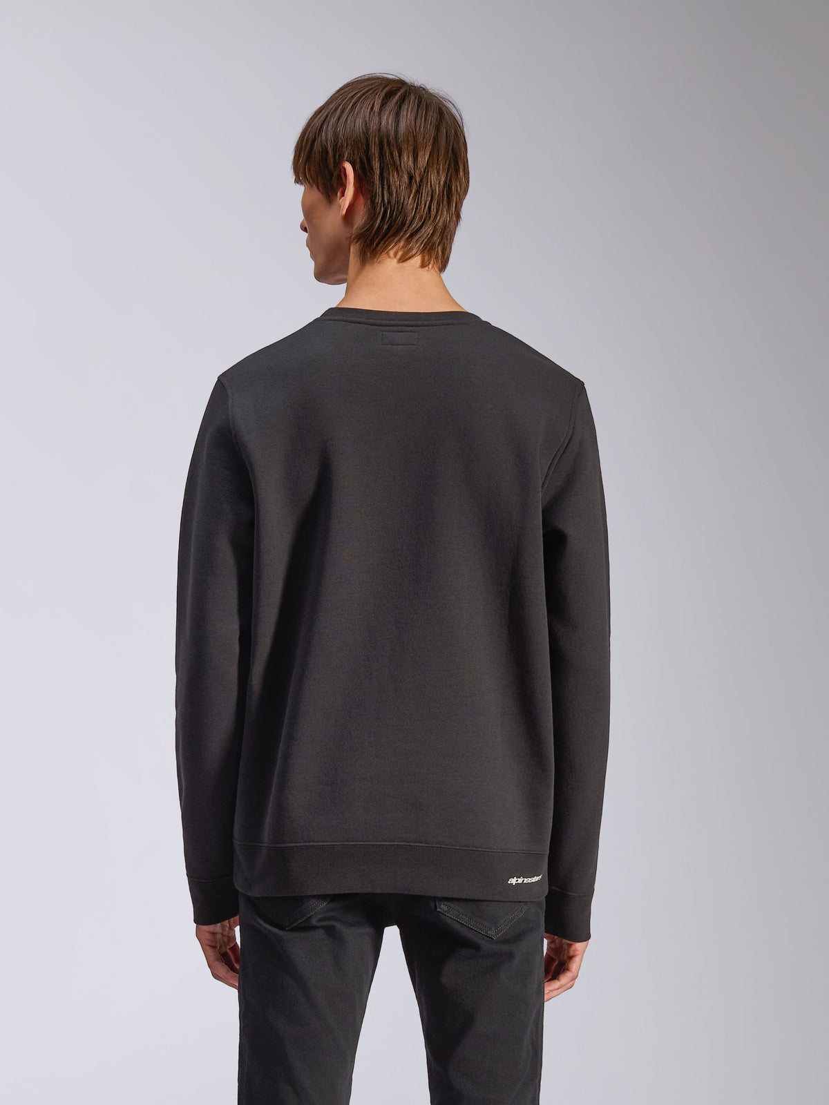 Alpinestars Positive Crew, Pullover-Sweatshirt, Schwarz, Rückansicht, mit gerippten Bündchen und Saum sowie einem kleinen weißen Logo an der Hüfte, lässiges, vom Motorsport inspiriertes Design