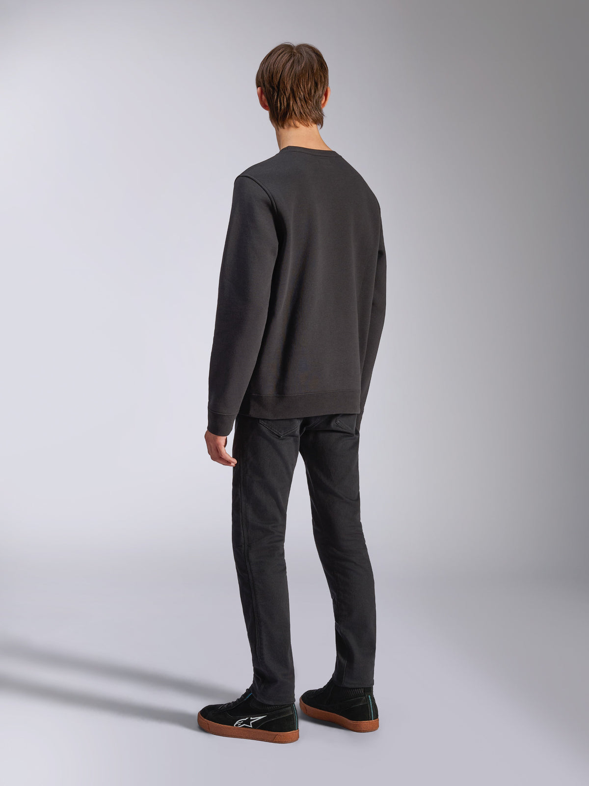 Alpinestars Positive Crew, schwarzes Pullover-Sweatshirt, Rückansicht am Model, lässige, vom Motorsport inspirierte Streetwear, mit Rippbündchen an Saum und Ärmeln