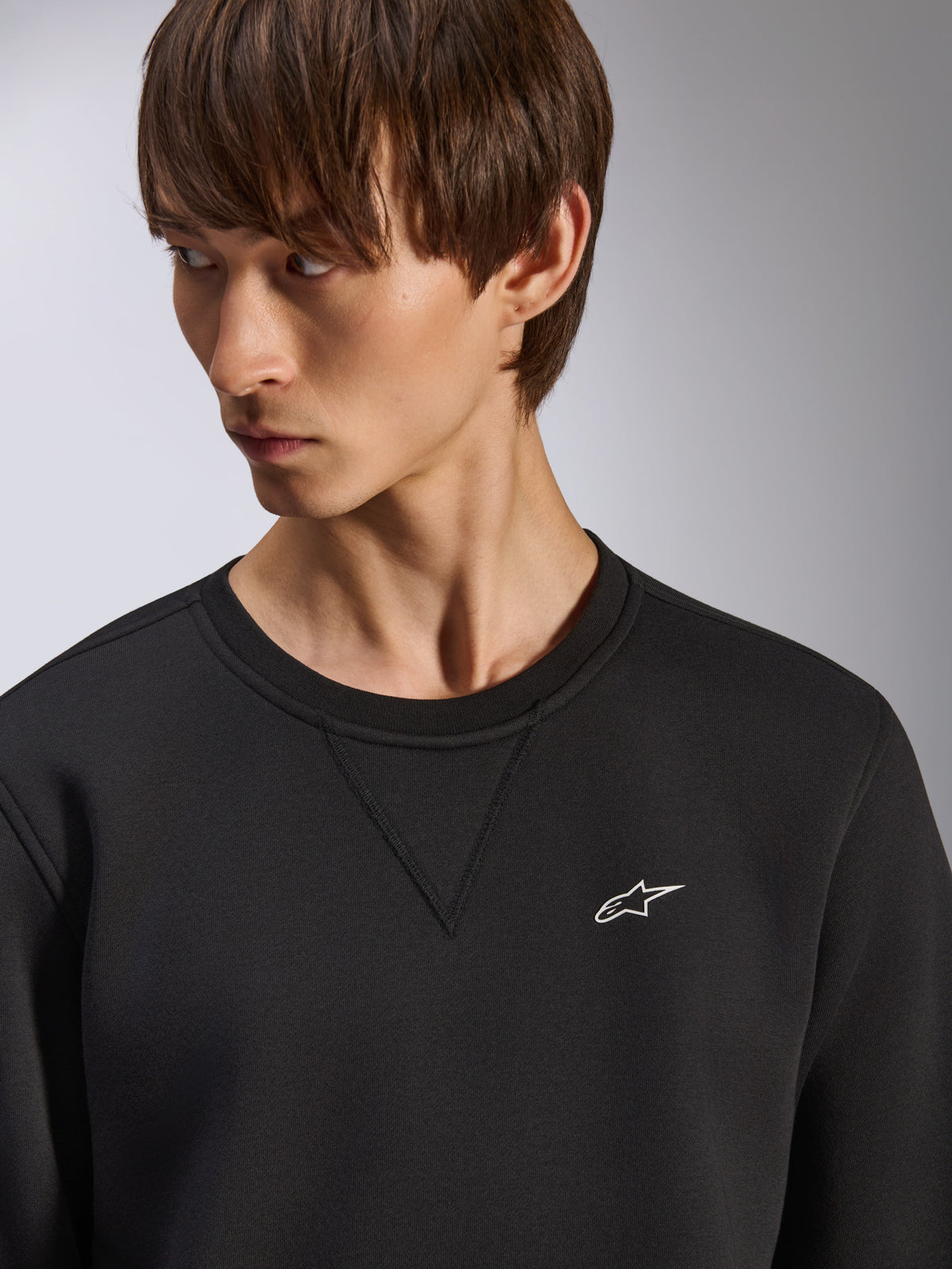 Alpinestars Positive Crew Sweatshirt, schwarzer Rundhalsausschnitt mit V-Naht-Detail am Kragen, kleines weißes Alpinestars-Logo auf der linken Brust, lässige motorsport-inspirierte Streetwear