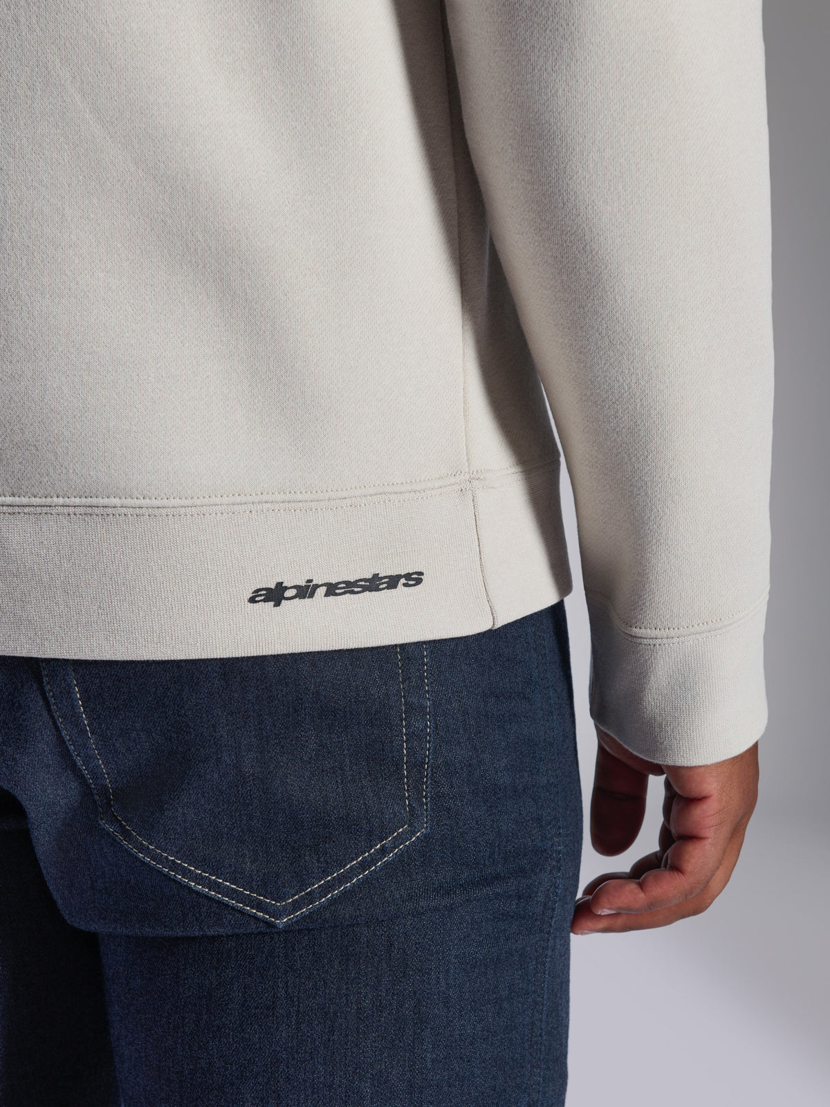Alpinestars Positive Crew Sweatshirt, Off-White, Nahaufnahme von Rippsaum und Ärmelbündchen, mit kleinem schwarzem Alpinestars-Logo, lässige, vom Motorsport inspirierte Bekleidung