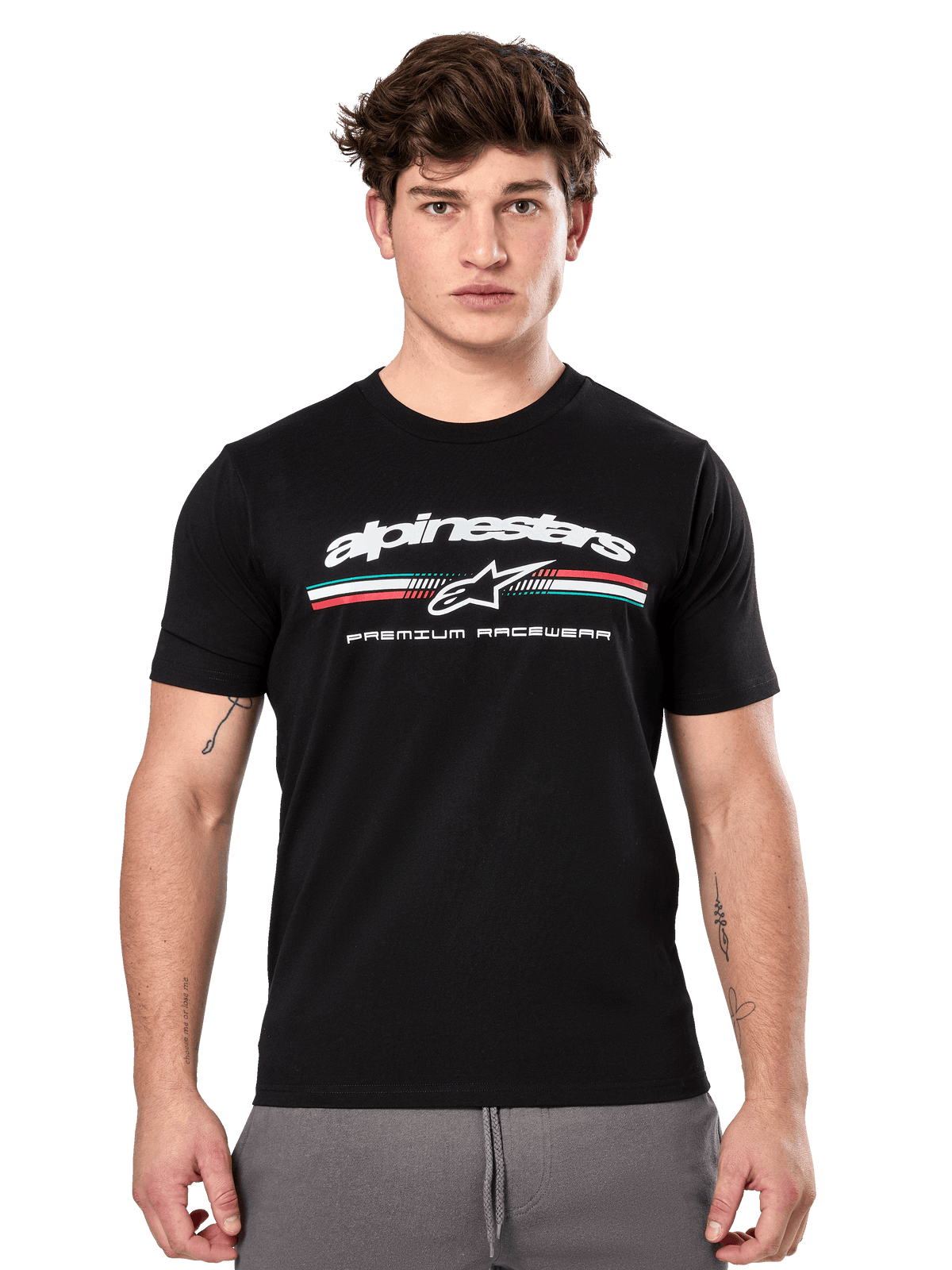 Alpinestars Prevail CSF Tee, schwarzes Kurzarm-T-Shirt an einem Model, weißes Branding mit dreifarbigem Streifen und „PREMIUM RACEWEAR“-Grafik, lässige Motorsport-Streetwear