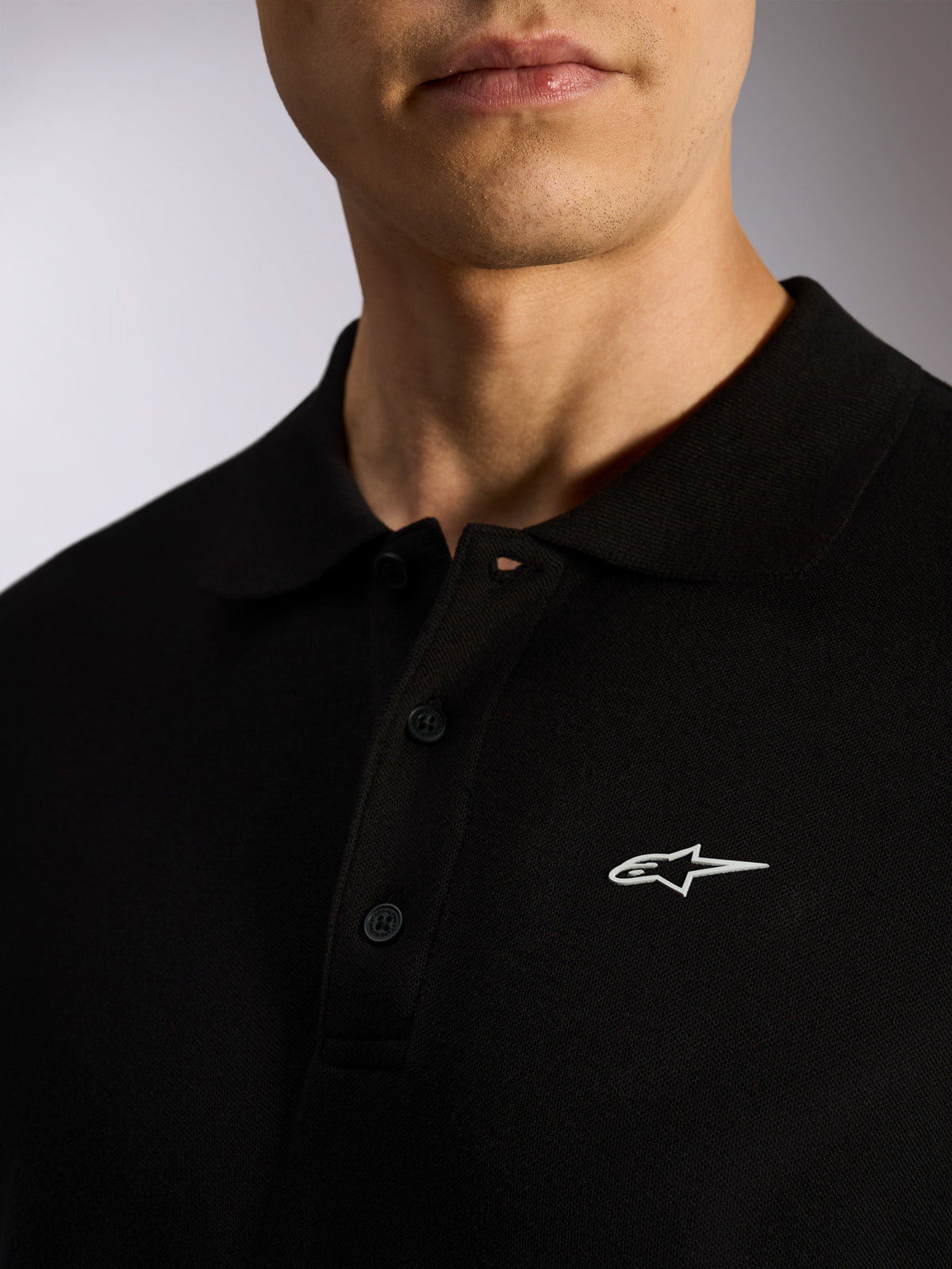 Alpinestars Endeavor Classic Polo, schwarzes Piqué-Kurzarmpoloshirt, 3-Knopf-Leiste, Rippkragen, weißer Astars-Logo-HD-Druck, lässige Motorsport-inspirierte Streetwear