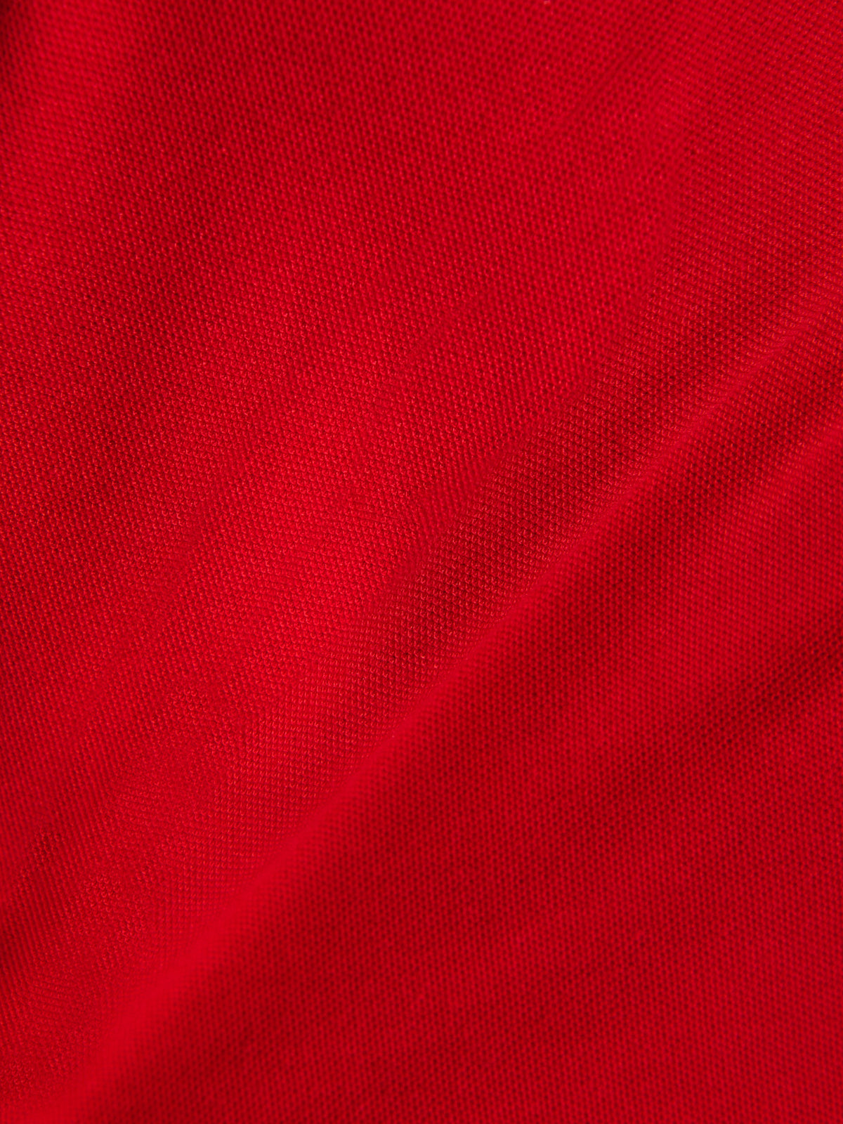 Alpinestars Endeavor Classic Polo, Detailaufnahme von rotem Piqué-Stoff, strukturiertes Strickmaterial, Baumwoll-Polyester-Mischung, lässige Motorsport-Sportbekleidung