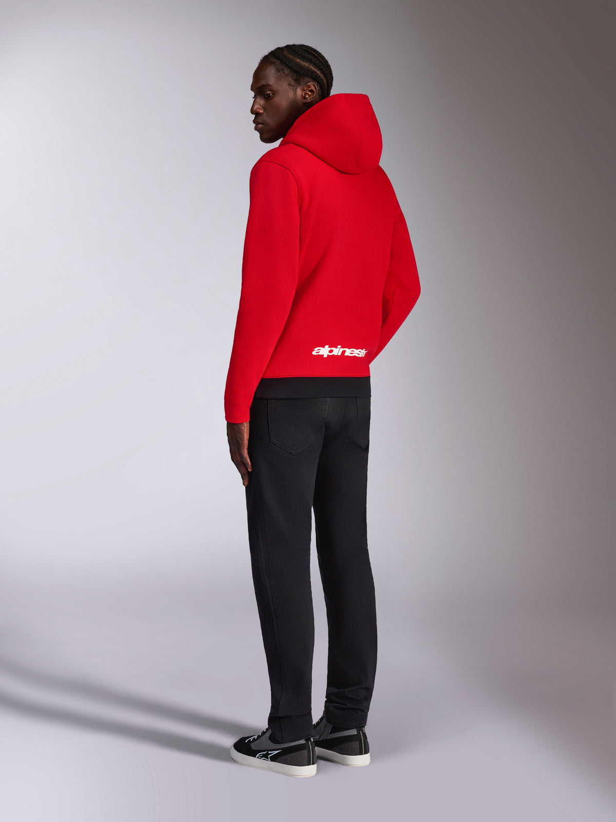 Alpinestars Parallel Kapuzenpullover, Rückansicht eines roten Fleece-Pullovers mit schwarzem Rippsaum, weißes Alpinestars-Logo auf dem unteren Rücken, lässiger Motorsport-Streetwear-Stil