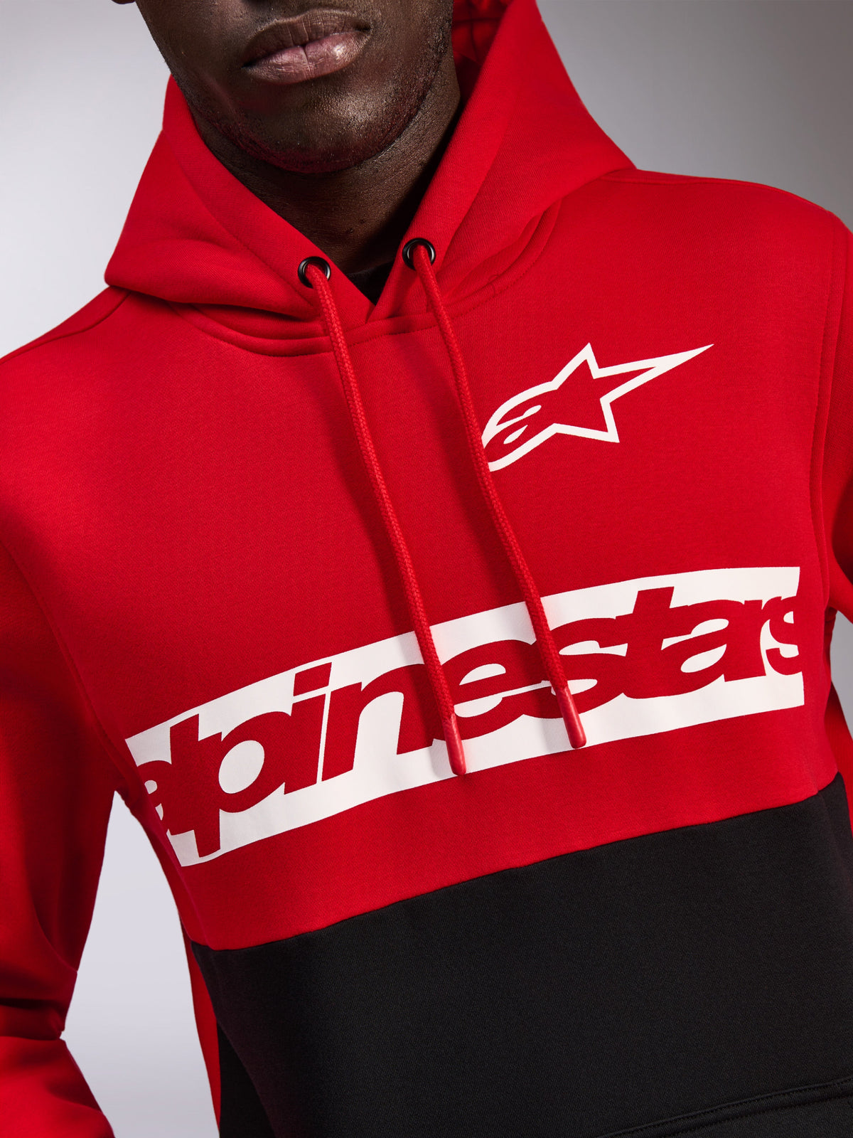 Alpinestars Parallel Hoodie, Fleece-Kapuzenpullover im Color-Block-Design in Rot und Schwarz, mit weißem Astars-Logo und rotem Alpinestars-Schriftzug auf einem weißen Bruststreifen, Kapuze mit Kordelzug, lässige Motorsport-inspirierte Streetwear