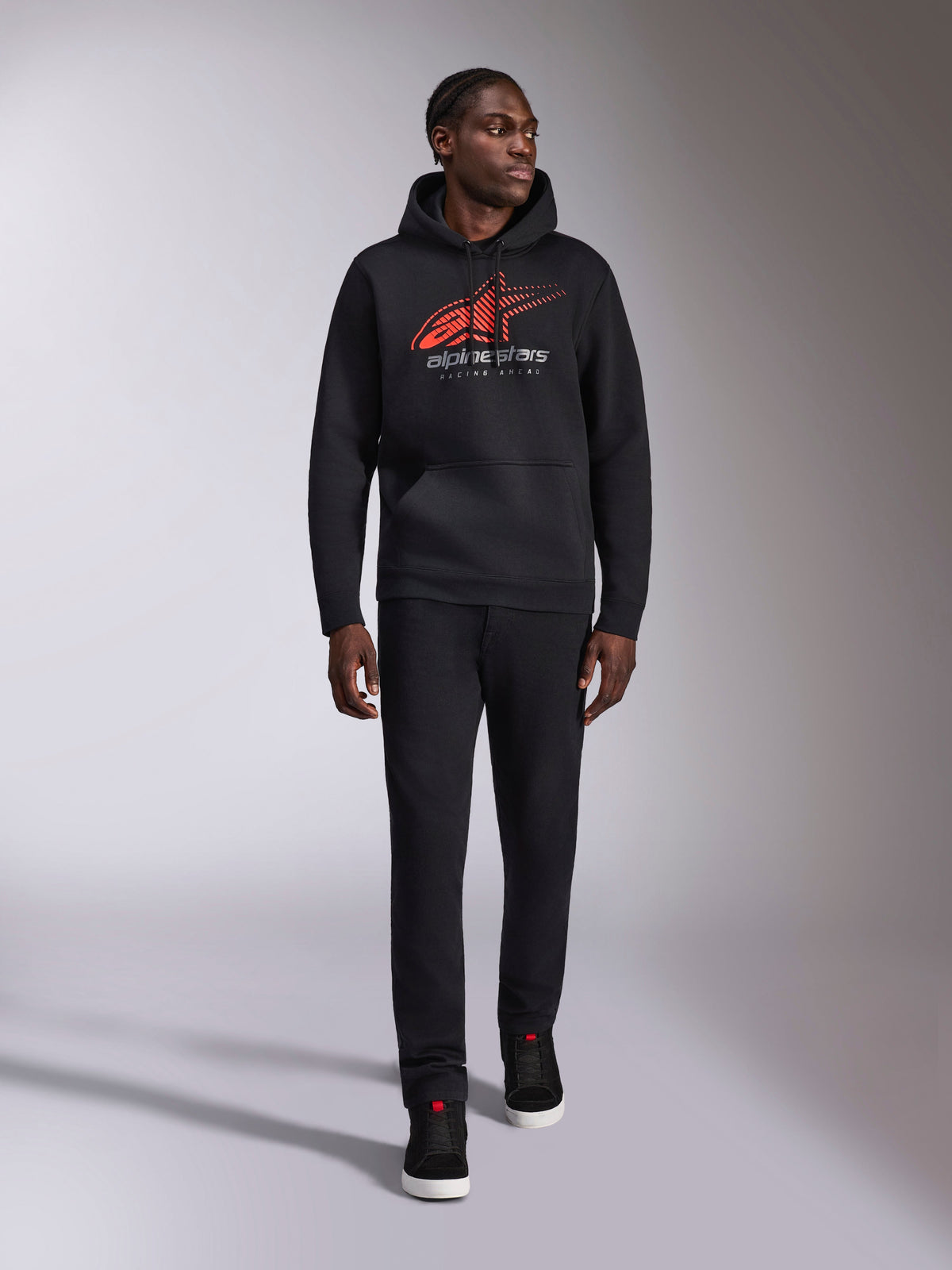 Alpinestars Pulse Hoodie, black casual streetwear hoodie, red and gray Astars combo logo with speed line fade on chest, drawstring hood, front pouch pocket, long sleeves, paired with black pants and sneakers, motorsport-inspired design