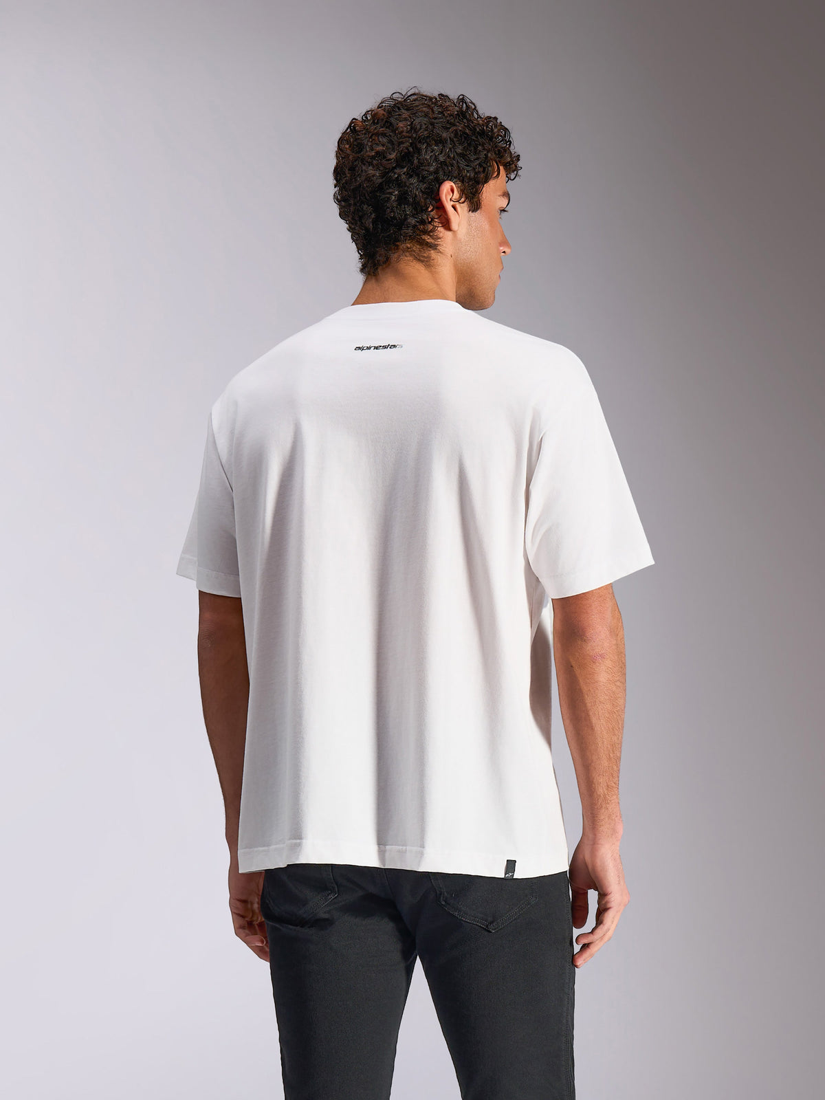 Alpinestars Focused Oversized CSF T-Shirt, kurzärmeliges T-Shirt, Weiß, Rückansicht am Modell mit kleinem schwarzem Alpinestars-Wortlogo unter dem Halsausschnitt, lockere Oversized-Passform, lässige Streetwear