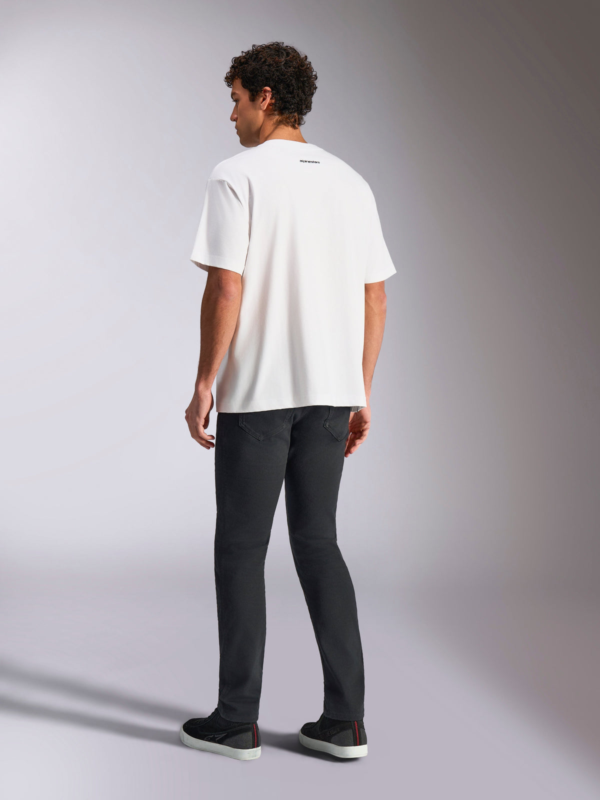 Alpinestars Focused Oversized CSF Tee, Kurzarm-T-Shirt, Weiß, kleines schwarzes Alpinestars-Wortlogo am Nacken, kombiniert mit schwarzer Hose, Oversized-Passform, lässige Motorsport-inspirierte Streetwear