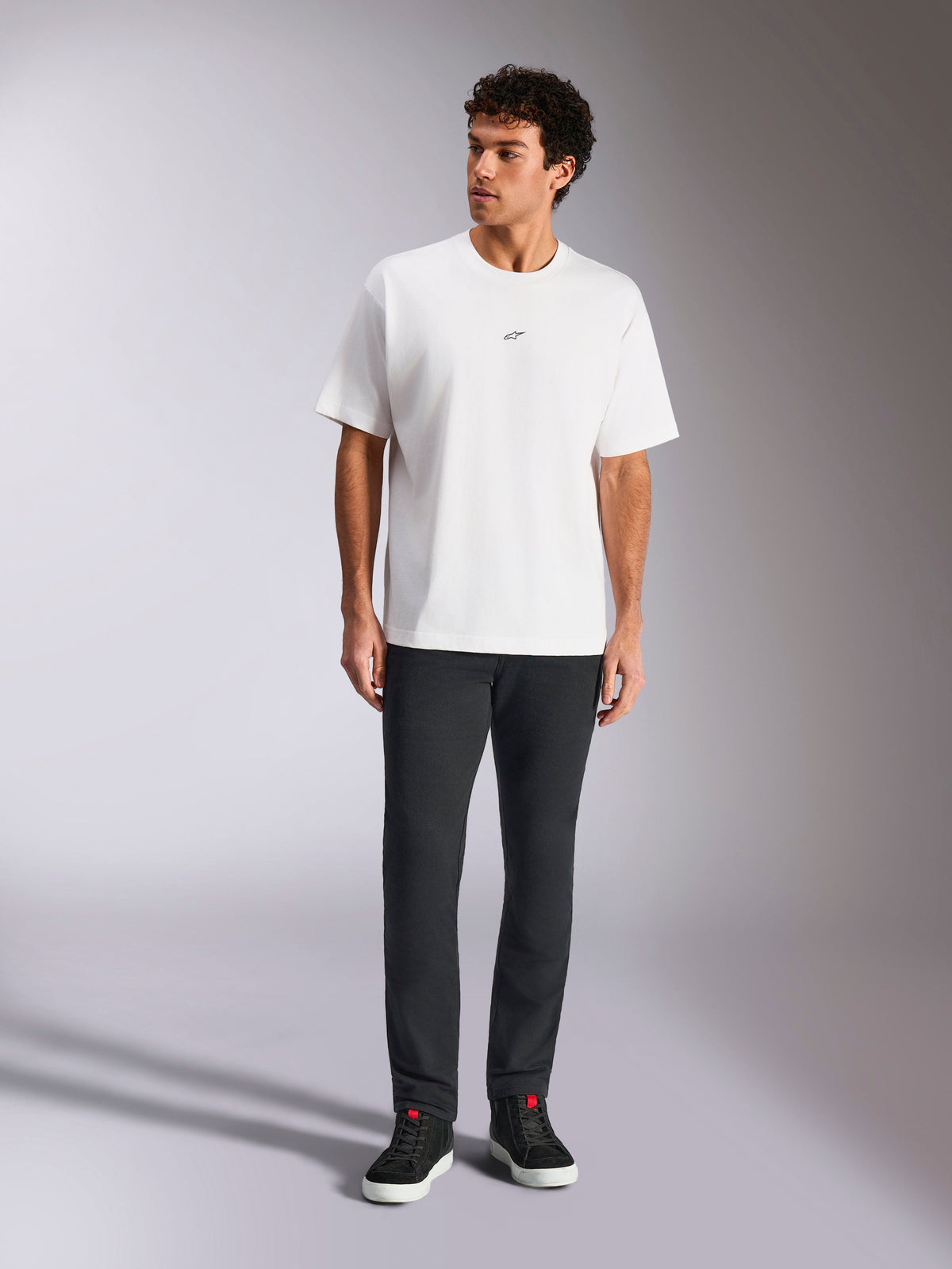 Alpinestars Focused Oversized CSF Tee, Kurzarm-T-Shirt, Weiß, kleines schwarzes Astars-Logo auf der Brust, lässiger Streetwear-Stil, getragen von einem Model mit dunkler Hose und schwarzen High-Top-Sneakern