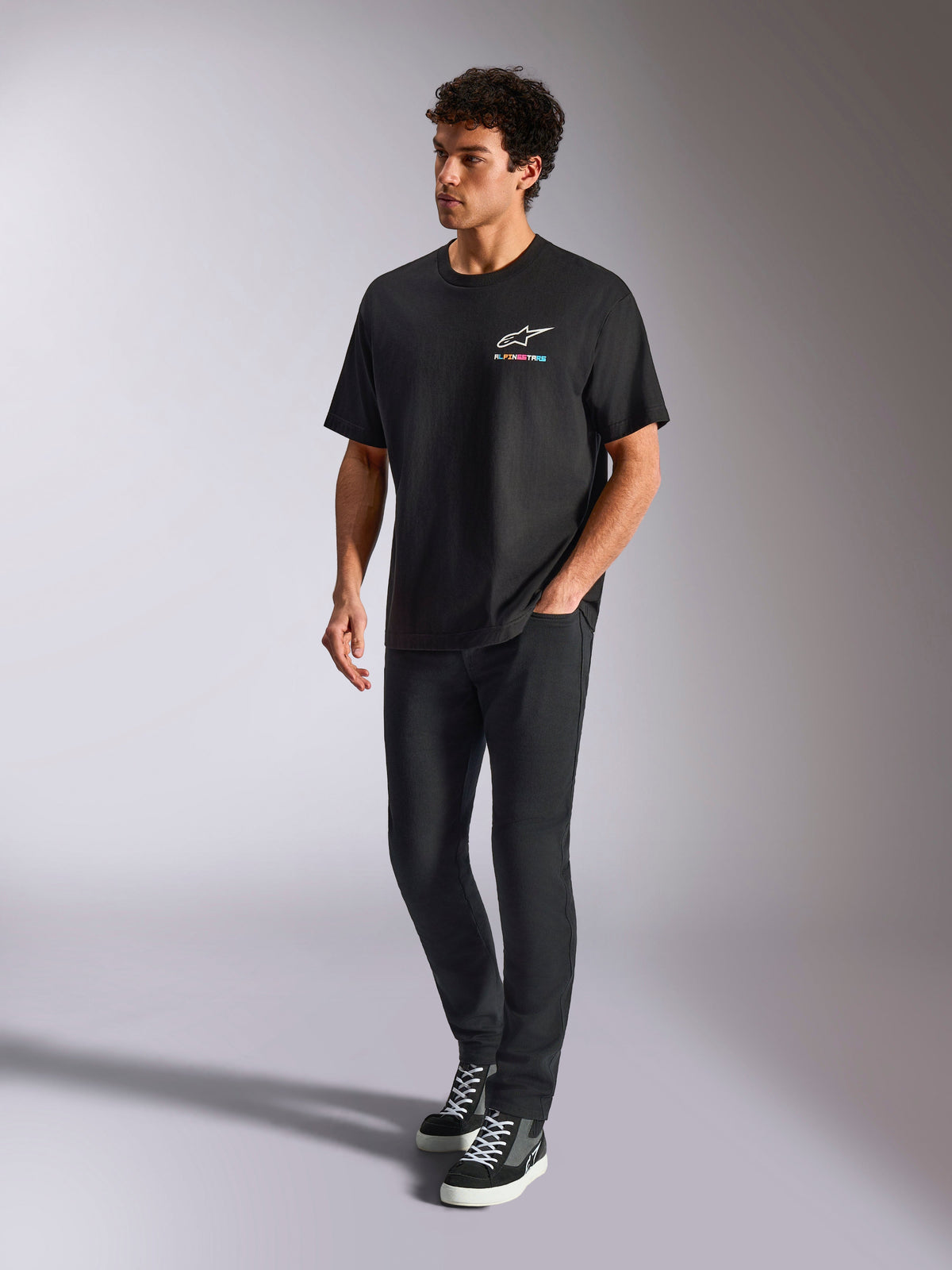 Alpinestars Wild Oversized CSF Tee, Short Sleeve T-Shirt, Black, multi-color Astars logo on the chest, casual streetwear style worn by a model with black pants and high-top sneakers