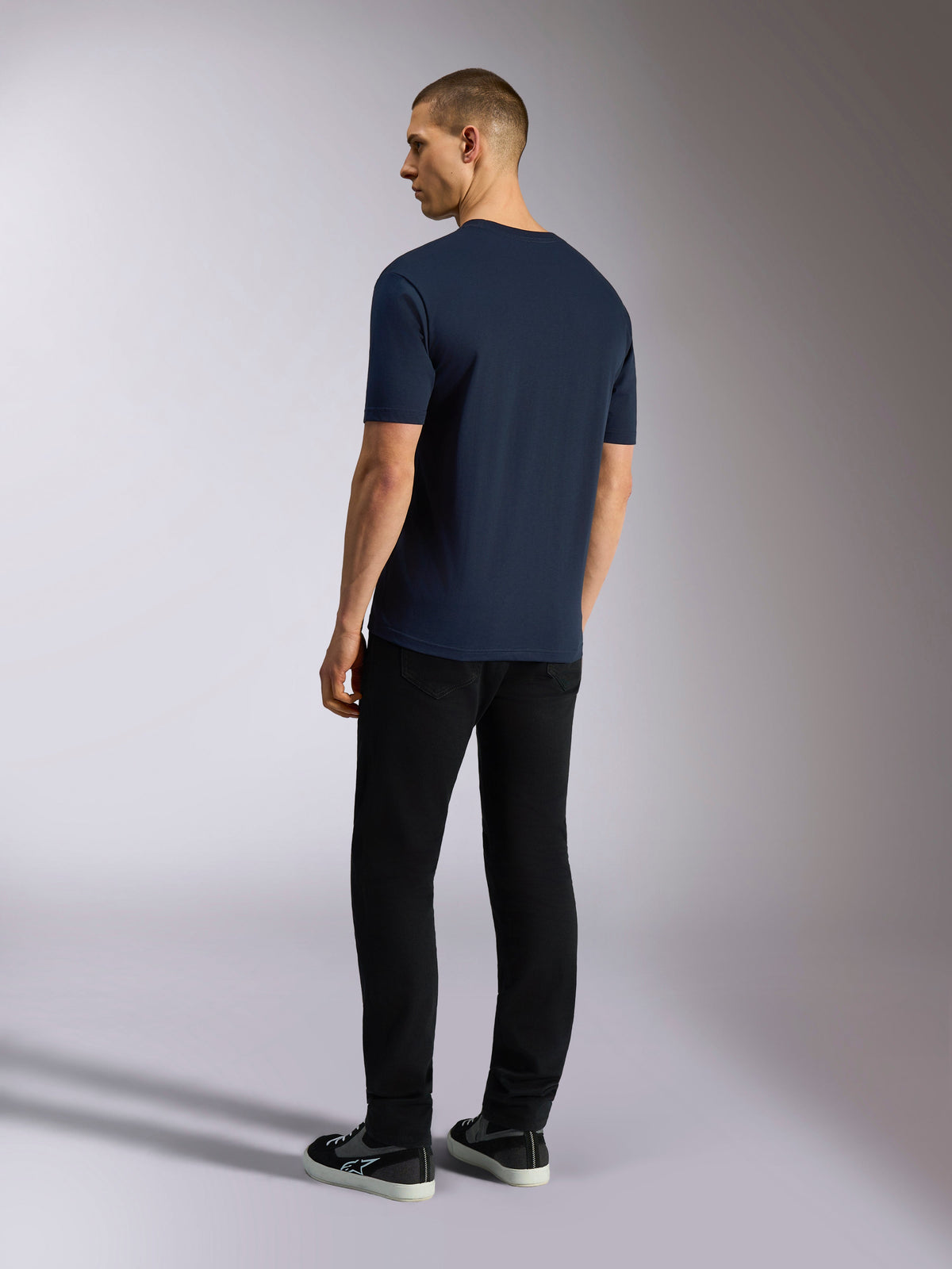 Alpinestars Noka CSF Tee, kurzärmeliges T-Shirt, Marineblau, Rückansicht an einem Model mit schwarzer Hose und Sneakern, lässige Motorsport-Streetwear