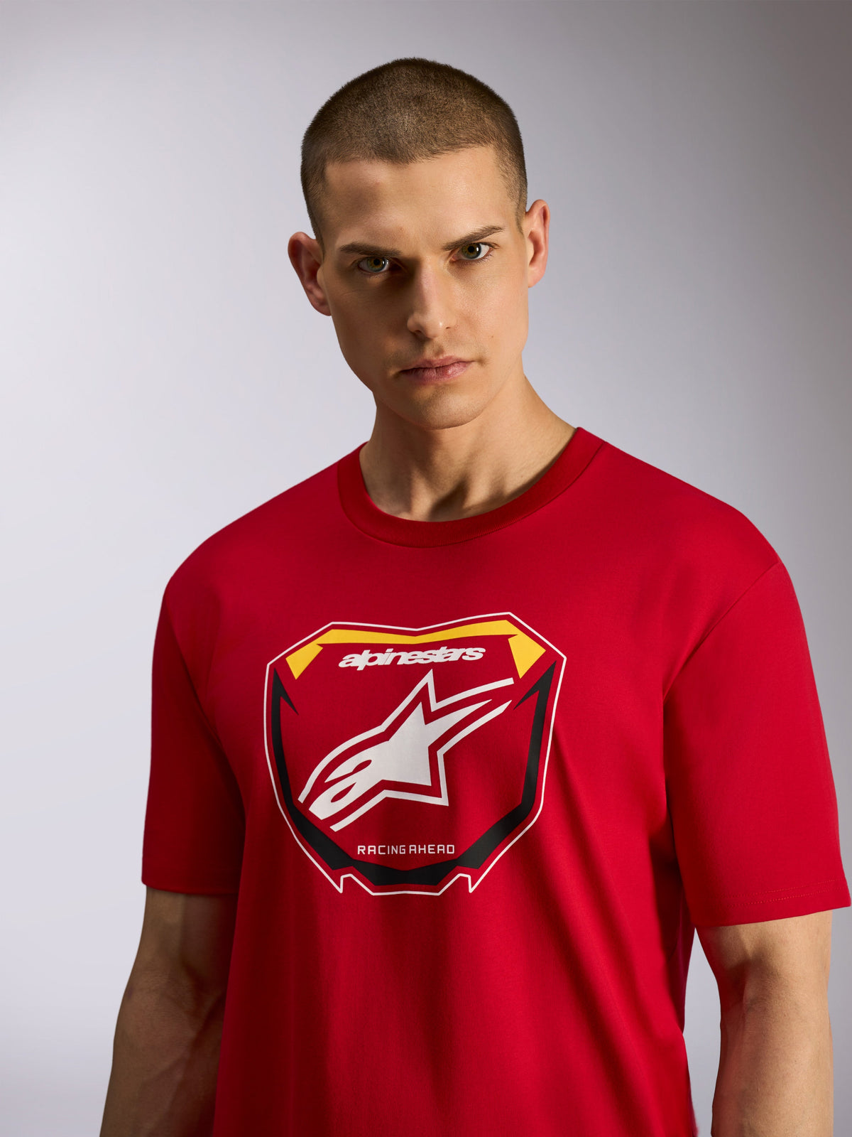 Alpinestars Plate CSF Tee, Short Sleeve T-Shirt, Red, featuring a front MX plate graphic with Alpinestars logo and 'Racing Ahead' text, worn by a male model, casual motorsport-inspired sportswear
