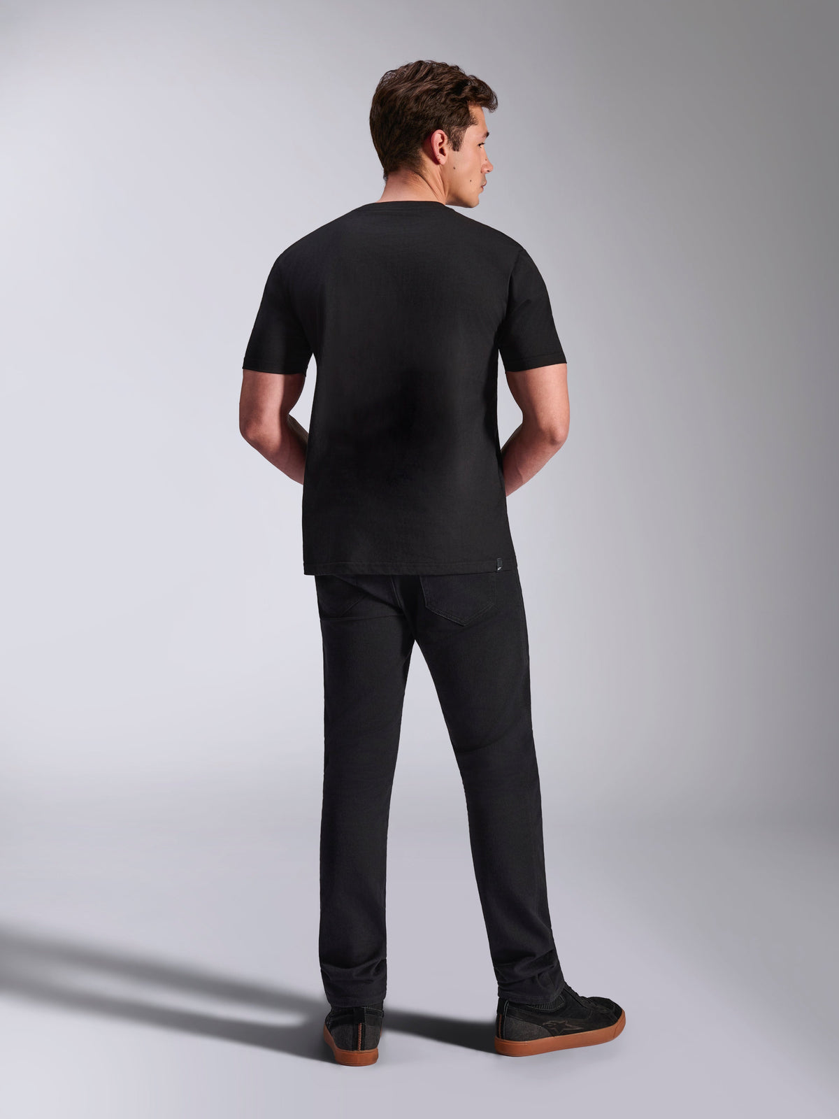 Alpinestars Abus CSF Tee, Kurzarm-T-Shirt, Schwarz, Rückansicht am Modell kombiniert mit schwarzer Hose, lässige Motorsport-Sportbekleidung