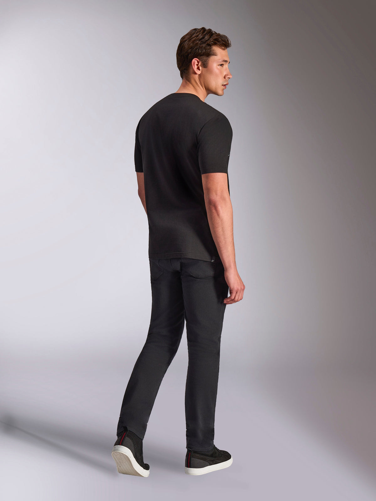 Alpinestars Trifecta CSF Tee, Kurzärmeliges T-Shirt, Schwarz, Rückansicht eines Mannes, der das Shirt mit schwarzen Jeans und Sneakern trägt, lässige Motorsport-Streetwear
