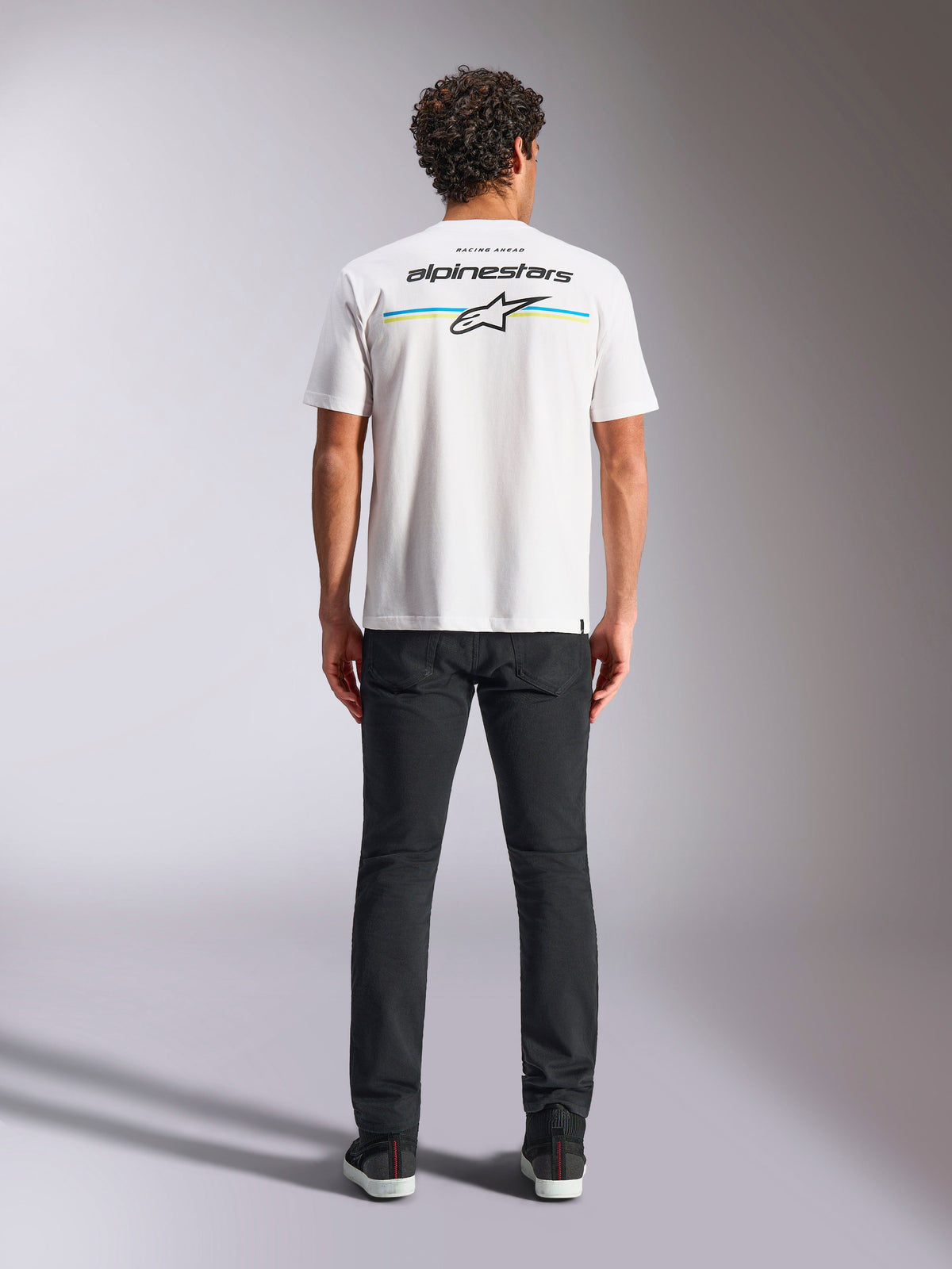 Alpinestars Lanes CSF Tee, Short Sleeve T-Shirt, White, back view on model featuring Alpinestars logo and Astars star over horizontal blue and yellow stripes, casual motorsport streetwear