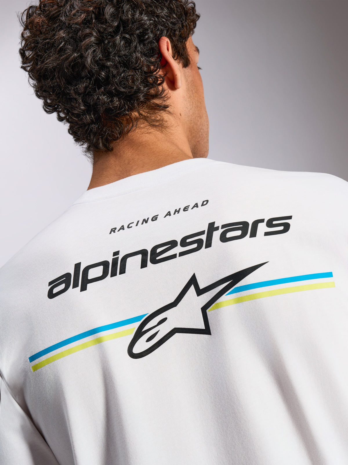 Alpinestars Lanes CSF Tee, Short Sleeve T-Shirt, White, back graphic with Alpinestars wordmark and Astars logo over blue and yellow stripes, casual motorsport-inspired streetwear