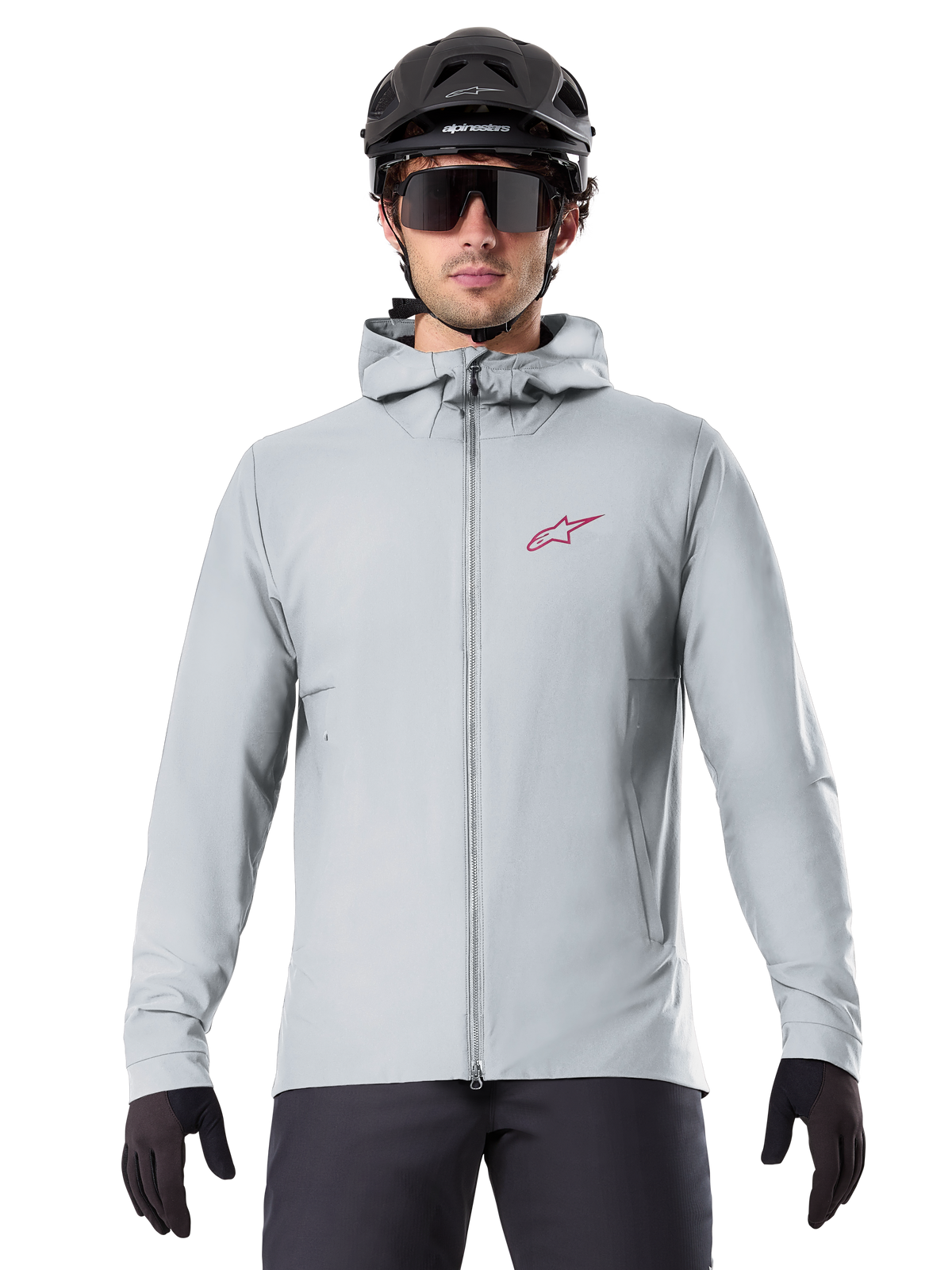 Alpinestars A-Dura Thermal Jacket in Titanium, light gray hooded cycling jacket with a red star logo on the chest, worn by a rider with a black MTB helmet, sunglasses, and gloves, insulated gear for mountain biking