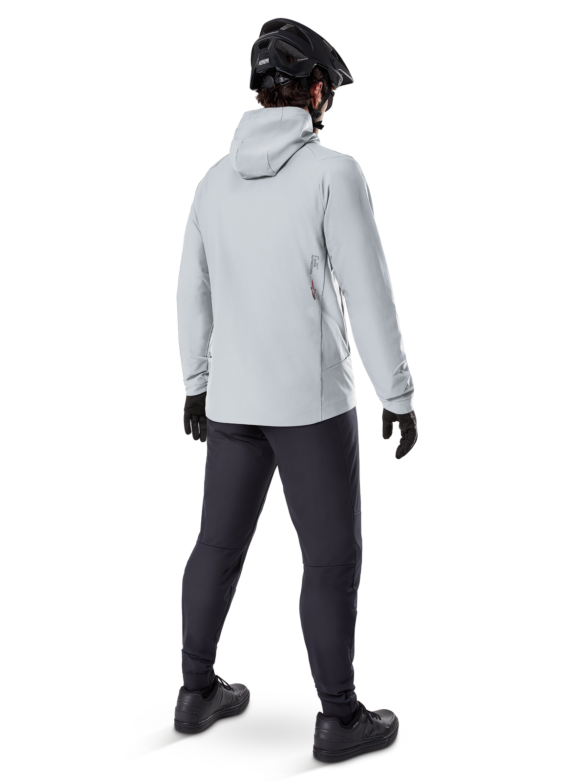 Alpinestars A-Dura Thermal Jacket in Titanium, back view of male cyclist wearing light gray hooded thermal jacket, paired with black MTB helmet, black gloves, and dark gray pants, functional mountain bike riding gear.