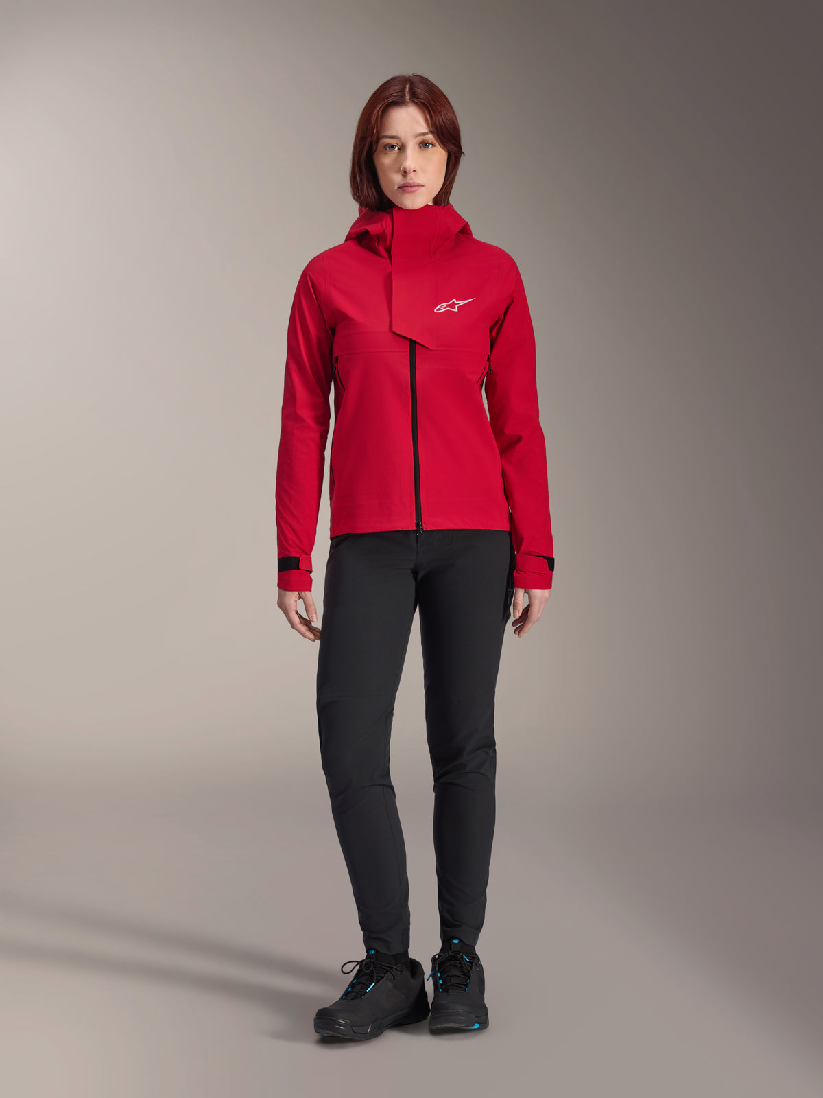 Alpinestars Stella A-Dura Elite Waterproof Jacket, Women's MTB Jacket, Red Fluo, worn with black pants and shoes, featuring a high-neck hood and white Alpinestars logo, technical mountain bike apparel