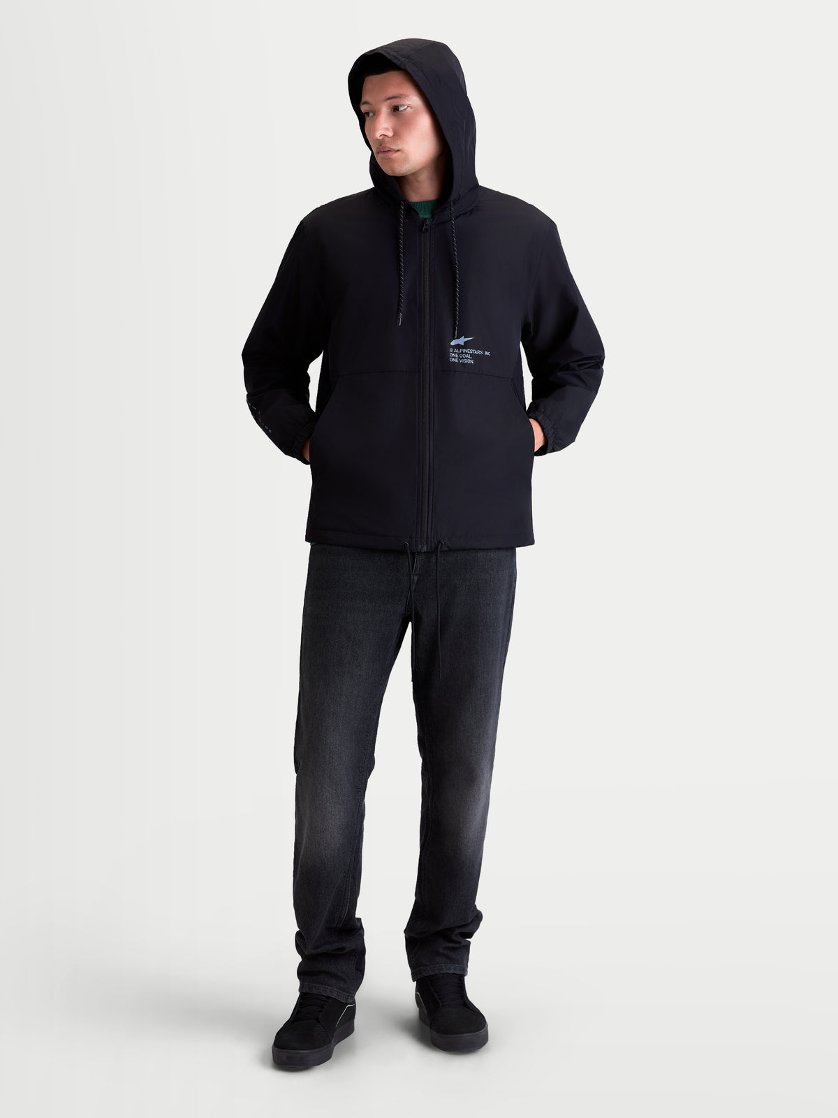 Alpinestars Speeder Resolve Winddichte Jacke, leichte Herren-Sportswear für den urbanen Einsatz, Schwarz, 100 % Polyester, mit verstellbarer Kapuze, Netzfutter und Alpinestars-Branding auf der Brust. Ganzkörperansicht am Modell der winddichten Kapuzenjacke für den täglichen Freizeit-Look.