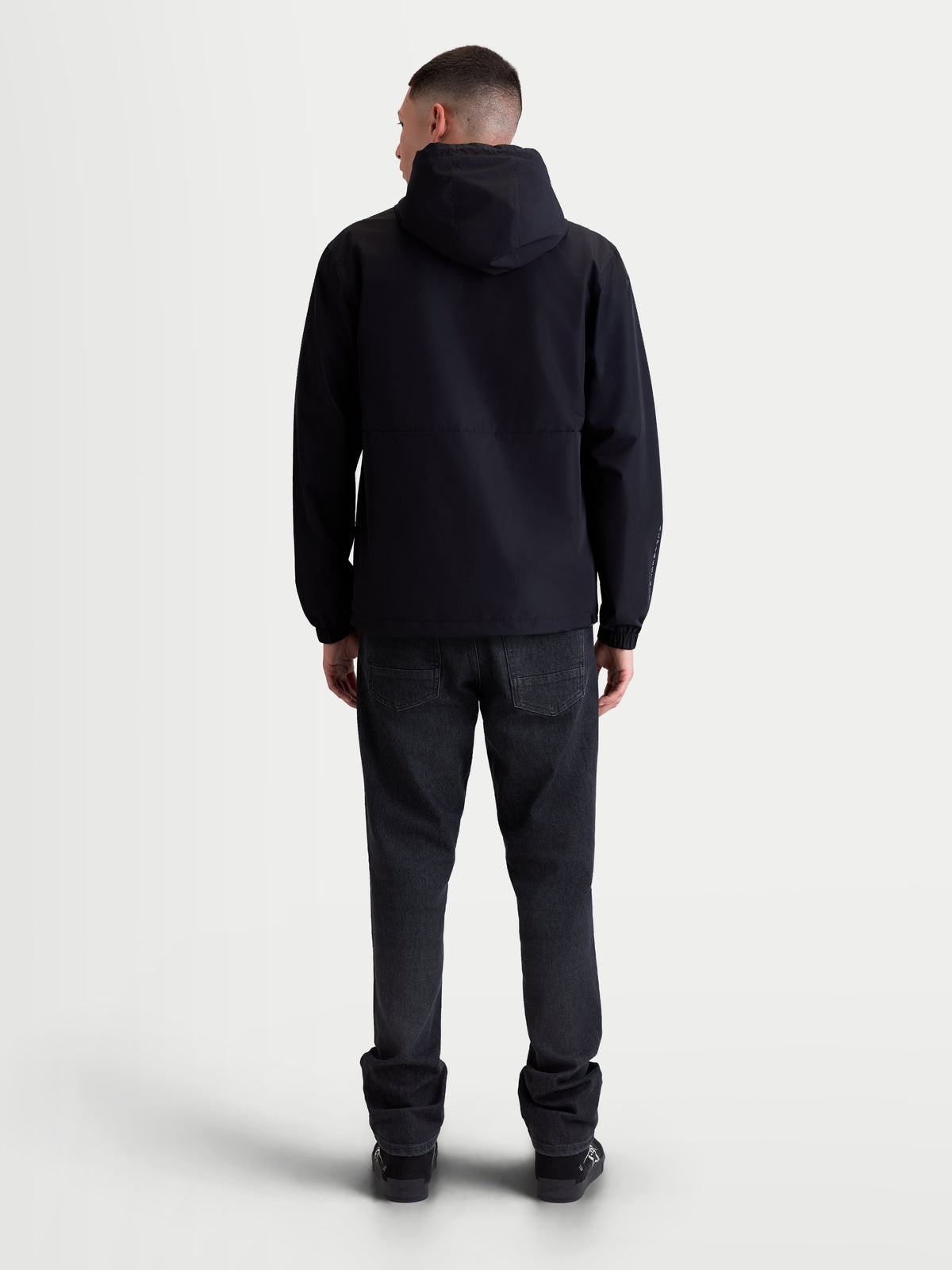 Alpinestars Speeder Resolve Winddichte Jacke, leichte Kapuzenjacke für den urbanen Einsatz, Schwarz, Rückansicht am Modell, atmungsaktive Konstruktion mit Netzfutter und verstellbarer Kapuze, Motorsport-Sportswear.