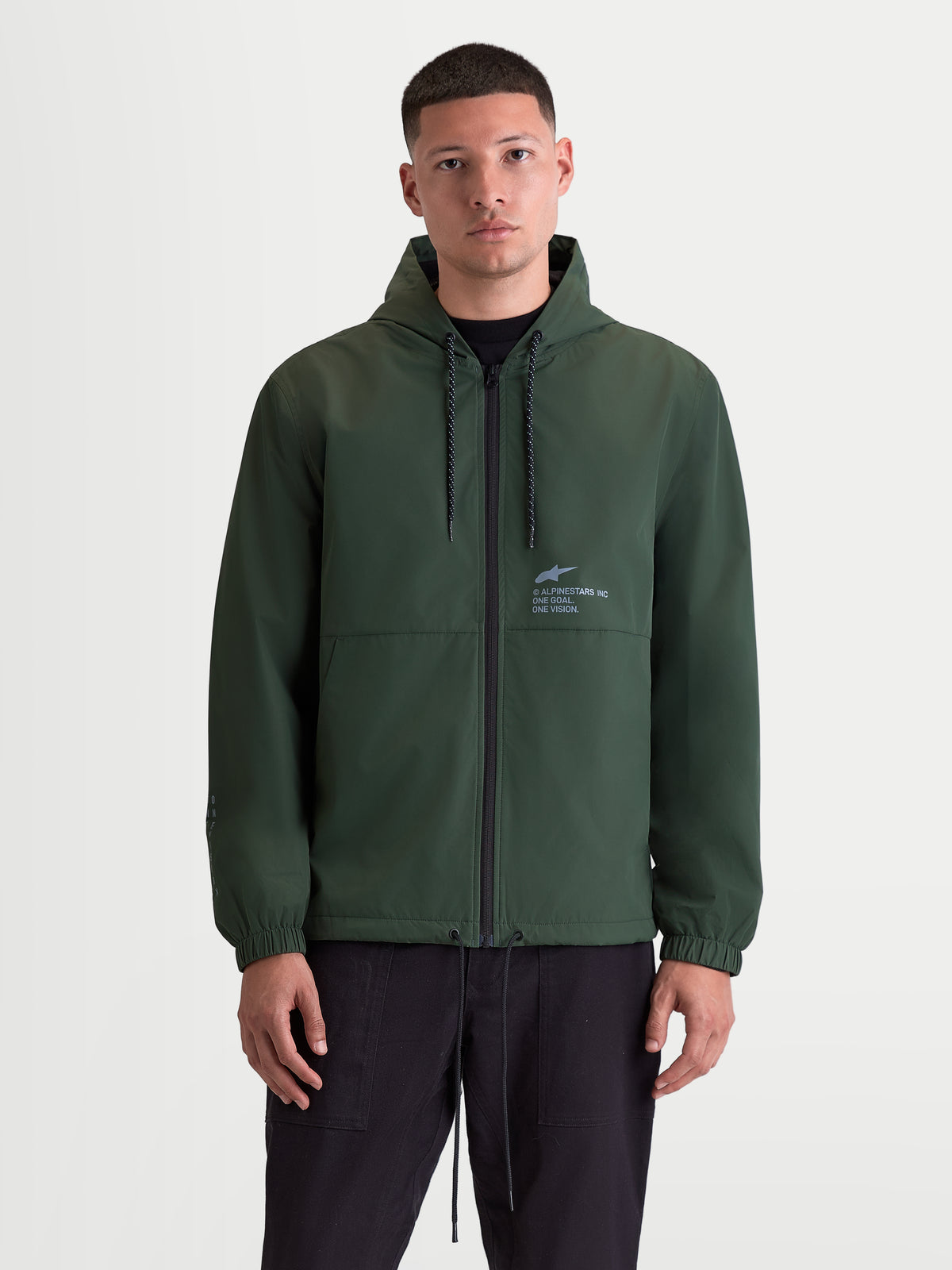 Alpinestars Speeder Resolve Winddichte Jacke, leichte Sportswear für den urbanen Gebrauch, Herren-Kapuzenjacke in Grün mit Netzfutter, verstellbarer Kapuze mit Kordelzug und Frontreißverschluss, Alpinestars Logo auf der Brust, Vorderansicht am Modell.