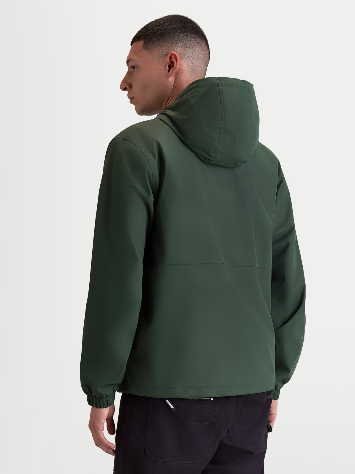 Alpinestars Speeder Resolve Winddichte Jacke, leichte Sportswear-Kapuzenjacke für den urbanen Einsatz, Kieferngrün, winddichtes Material aus 100 % Polyester mit Netzfutter, Rückansicht am Modell mit Fokus auf das cleane Rückendesign und elastische Bündchen.