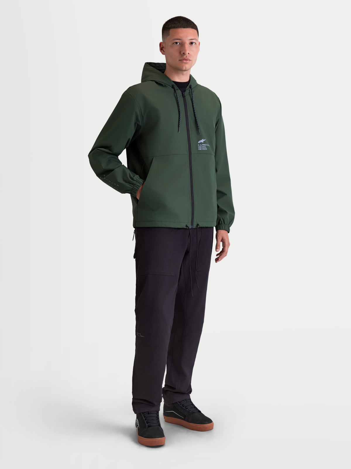 Alpinestars Speeder Resolve Winddichte Jacke, leichte Herren-Kapuzenjacke für den urbanen Einsatz, Grün, mit Netzfutter, verstellbarer Kapuze und Alpinestars-Logo auf der Brust, Motorsport-inspirierte Sportswear.