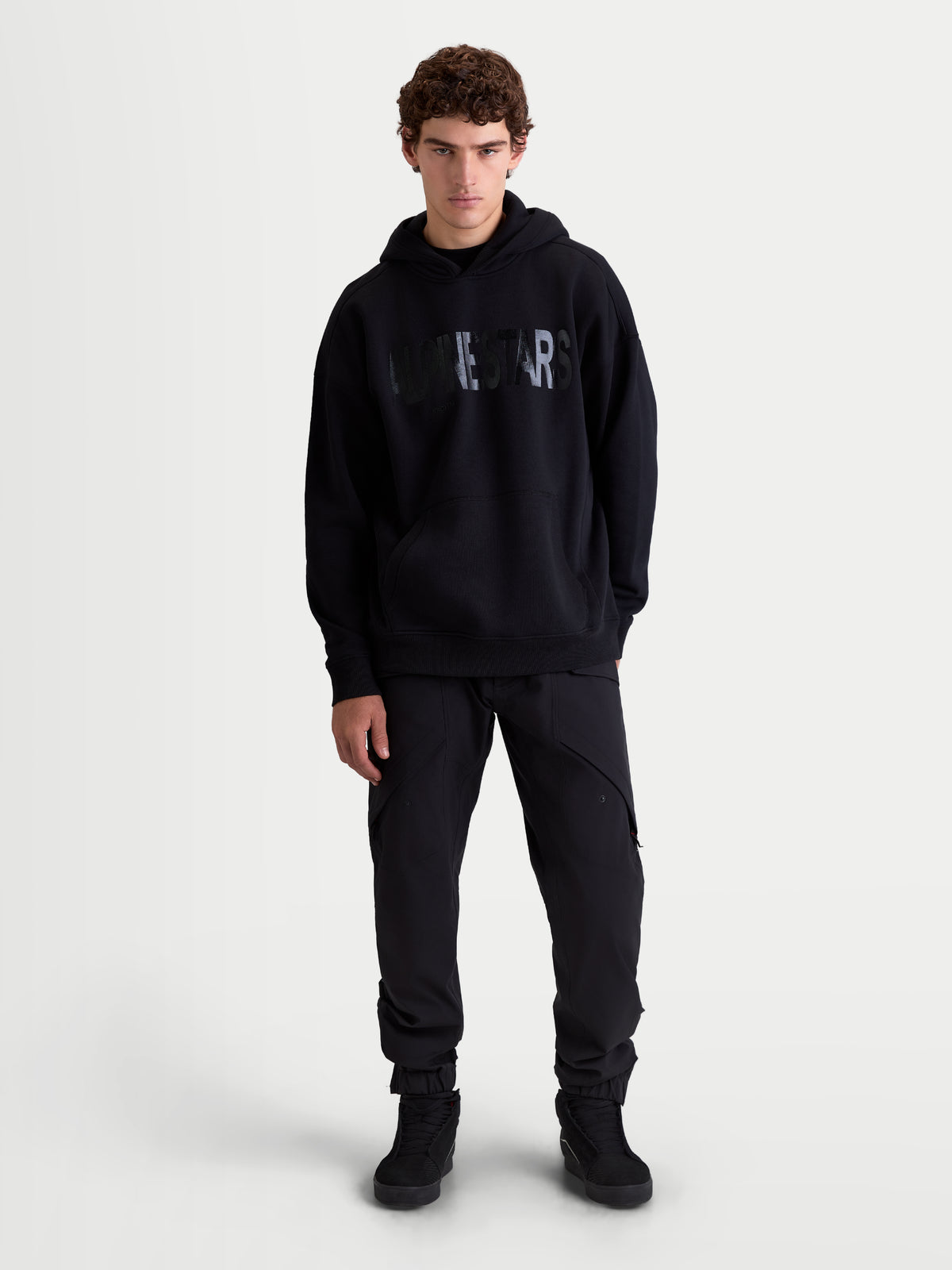 Alpinestars Shaw Oversize-Hoodie, Herren-Sportswear-Pullover in Schwarz, entspannte Passform aus Fleece mit strukturiertem Alpinestars Wortlogo auf der Brust, Kängurutasche und gefütterter Kapuze, Vorderansicht am Model.