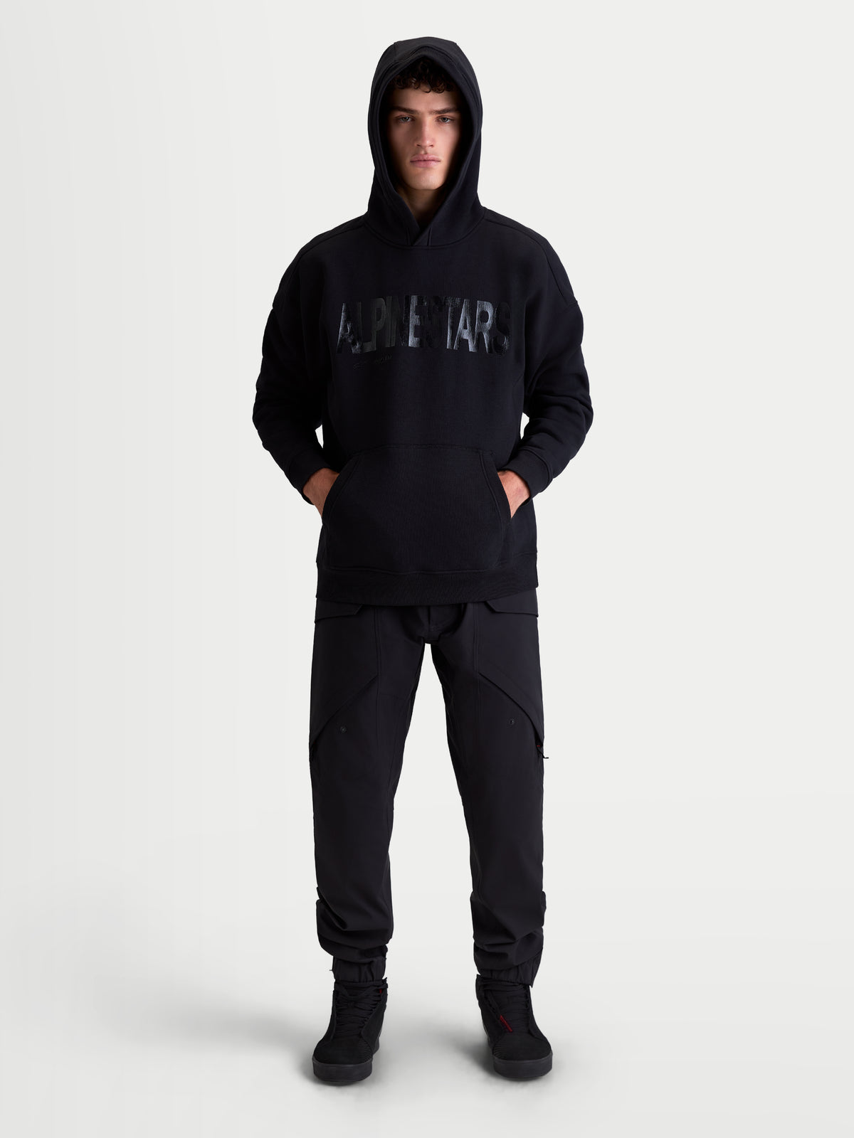 Alpinestars Shaw Oversize-Hoodie, Schwarz, entspannter Sportswear-Pullover für Herren und Damen, mit strukturiertem Alpinestars-Wortlogo auf der Vorderseite, Kängurutasche und selbstgefütterter Kapuze, hochwertige Konstruktion aus Baumwolle und recyceltem Polyester-Fleece.