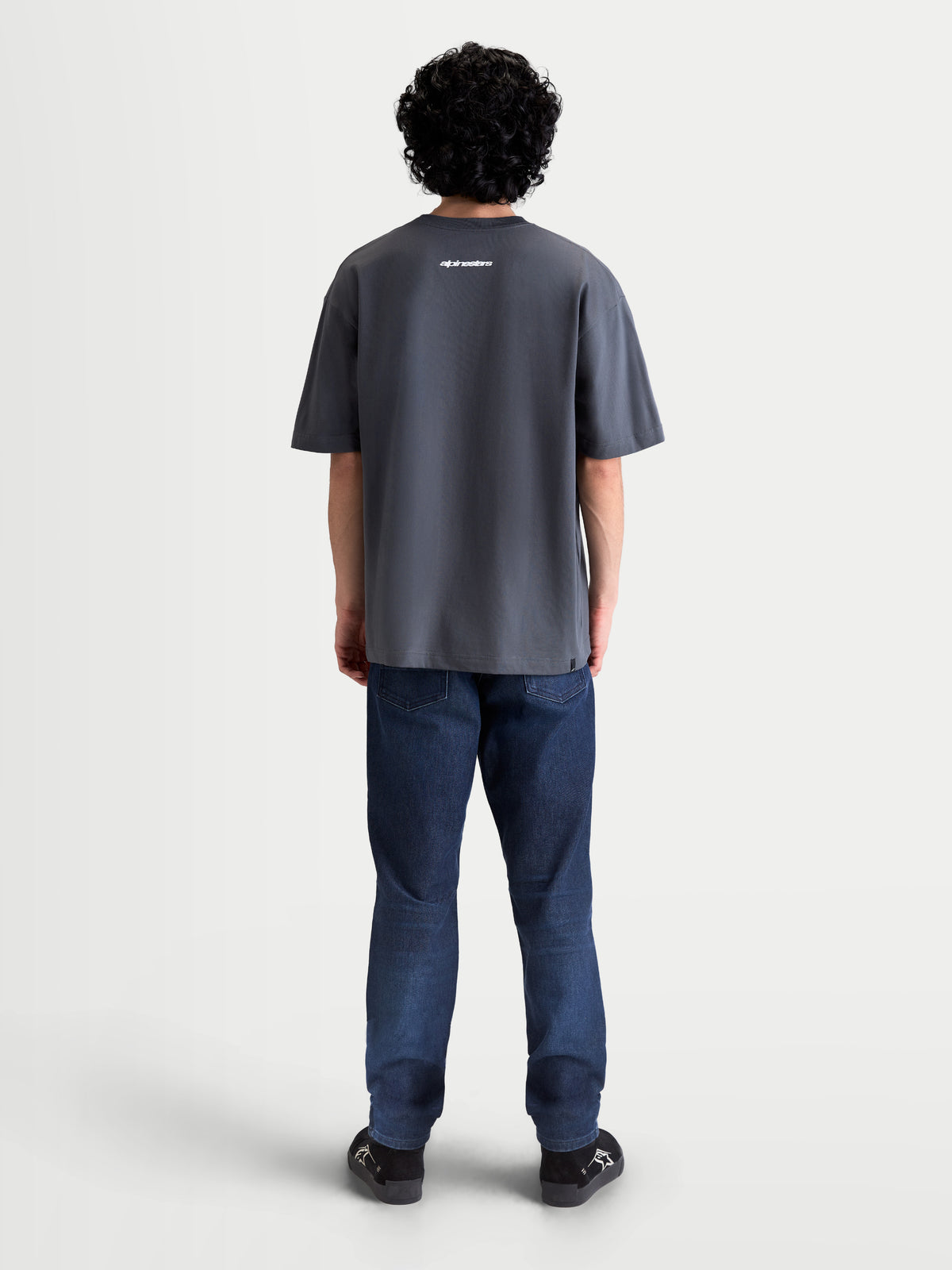 Alpinestars Mandate Oversized CSF T-Shirt, Kurzarm-Sportswear in Grau, Rückansicht am Model, lockere Oversized-Passform, weiße Alpinestars Wortgrafik auf dem Rücken, weicher Baumwoll-Polyester-Mix.