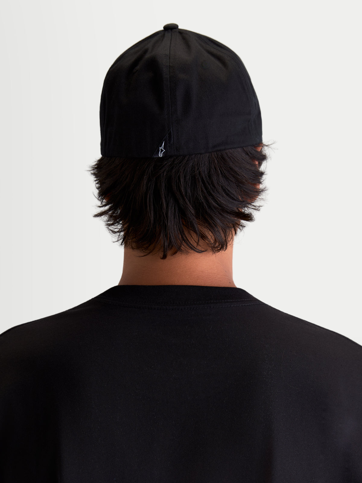Alpinestars Arclight Kappe, schwarze Sportswear Baseball-Kappe, Rückansicht am Modell, mit kleinem weißem Astars-Logo auf der Rückseite, strukturierte Krone und Flex-Back-Konstruktion, strapazierfähiger Baumwoll-Twill für täglichen Tragekomfort.