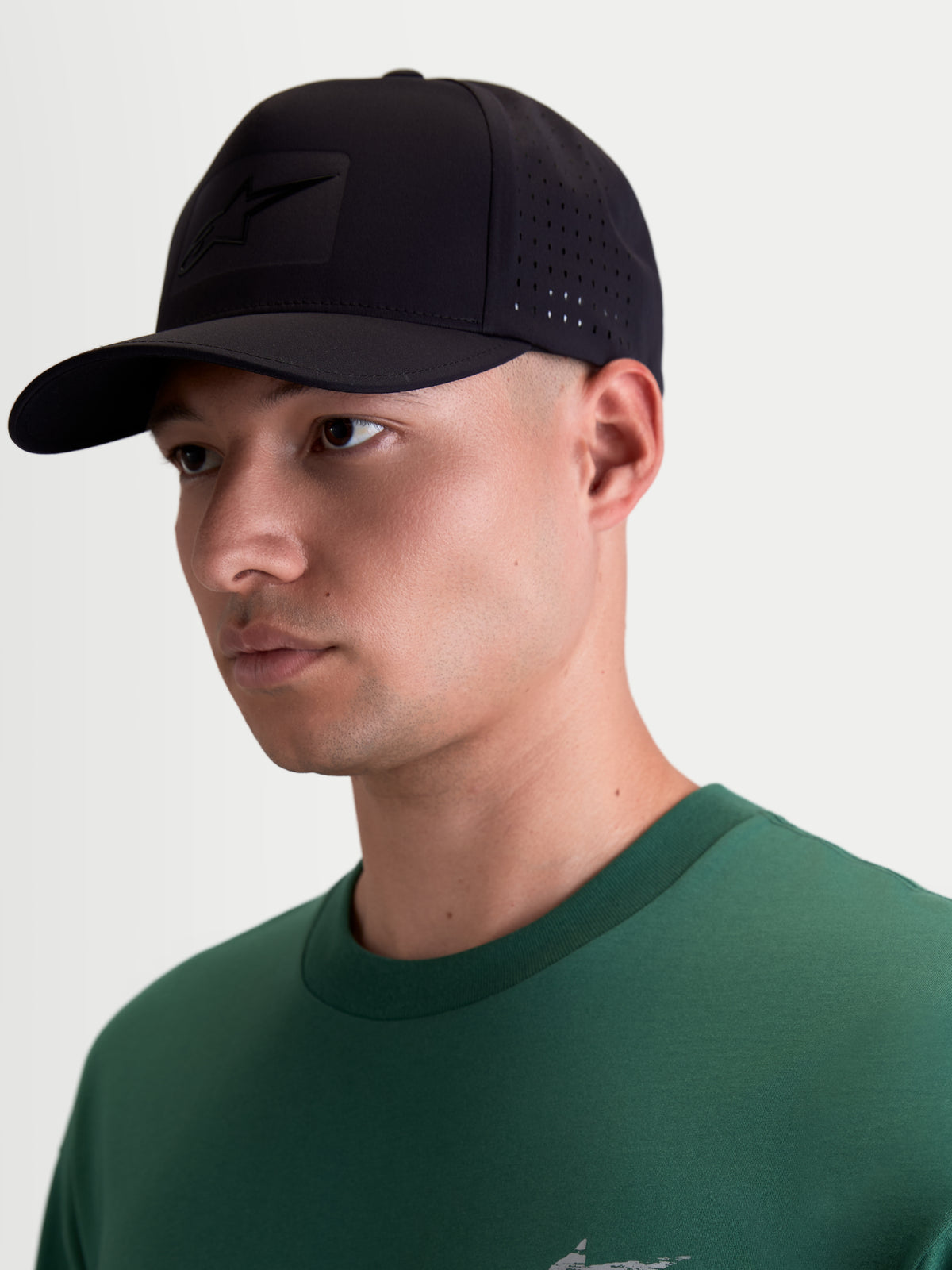 Alpinestars Algo Perf Adjustable Kappe, Motorsport-Sportswear-Kappe in Schwarz, Modell-Ansicht, technisches Gewebe mit seitlichen Perforationen zur Belüftung, gebogener Schirm und tonal abgestimmtes Sonic-Weld Astars-Logo.