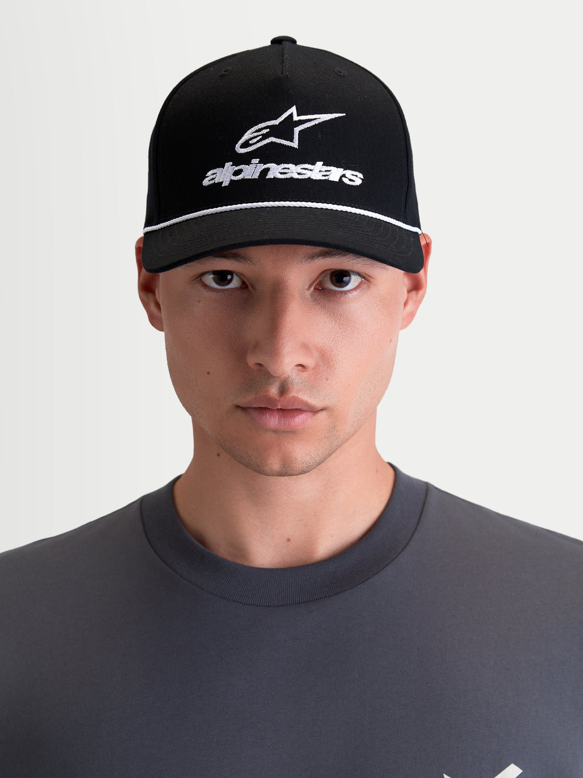 Alpinestars Combo Logo Snapback-Kappe, Motorrad-Sportswear-Kappe, Unisex, Schwarz und Weiß, mit gebogenem Schirm, strukturierter Krone und besticktem Astars-Logo, 100 % Baumwolltwill, Frontansicht am Model.