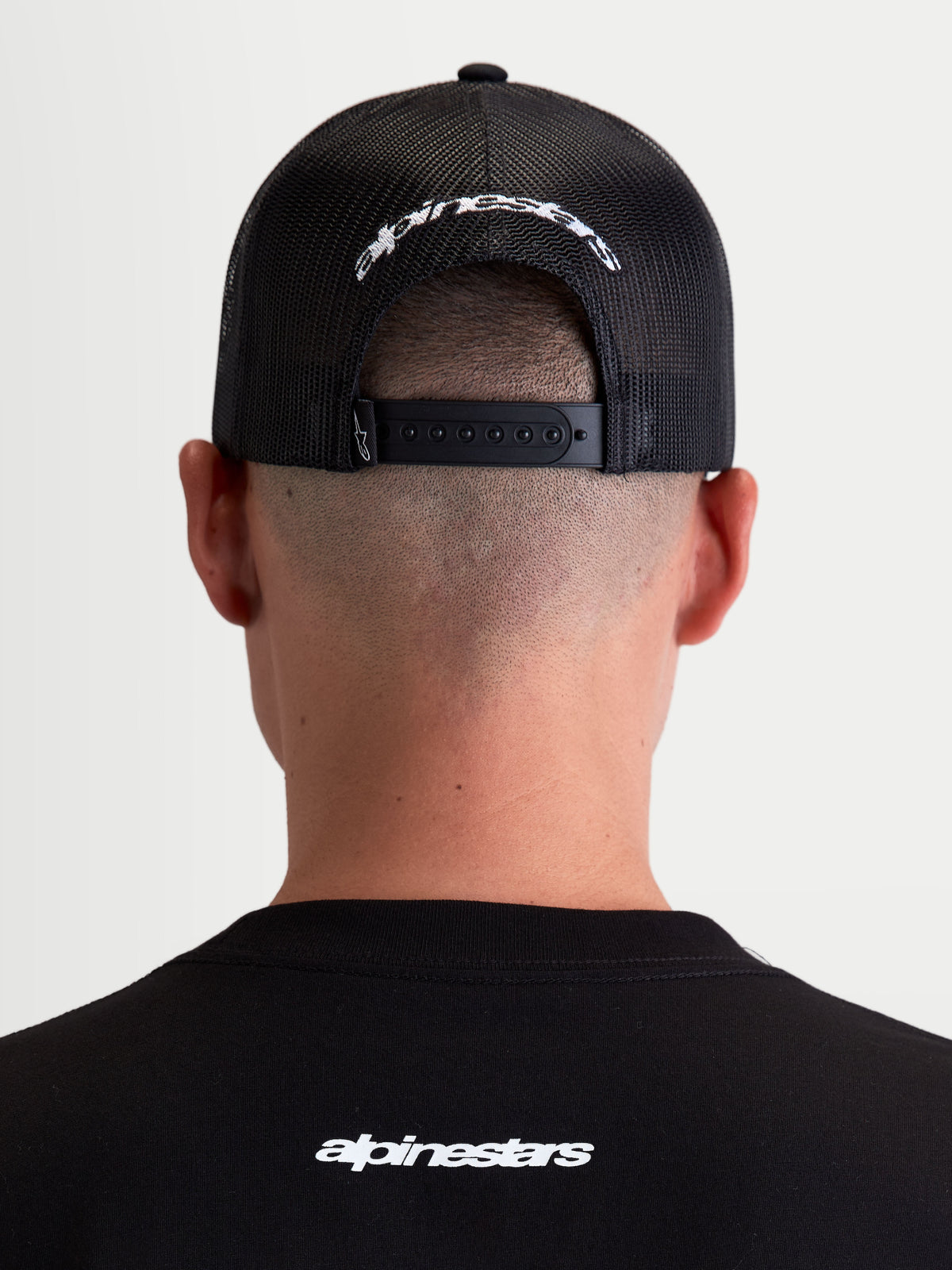 Alpinestars Meteorite Trucker-Kappe, Sportswear-Kappe mit Mesh-Rückseite, Schwarz und Weiß, verstellbarer Snapback-Verschluss und weiß gesticktes Alpinestars-Logo auf der Rückseite, Rückansicht am Modell.
