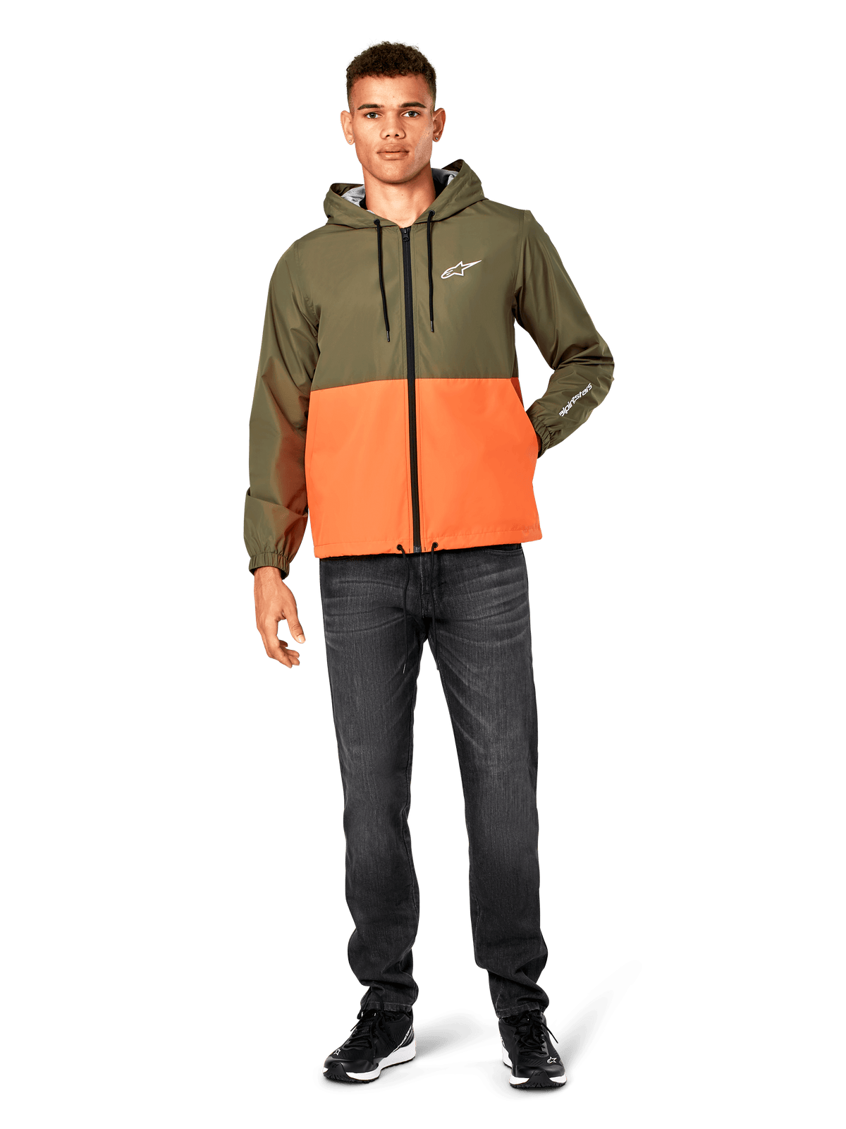 Alpinestars Speeder Windbreaker Jacket, color-blocked Military Green and Orange, lightweight hooded jacket with black drawcords and front zipper, white logo on chest and sleeve, worn with dark jeans and black sneakers, casual sportswear style.