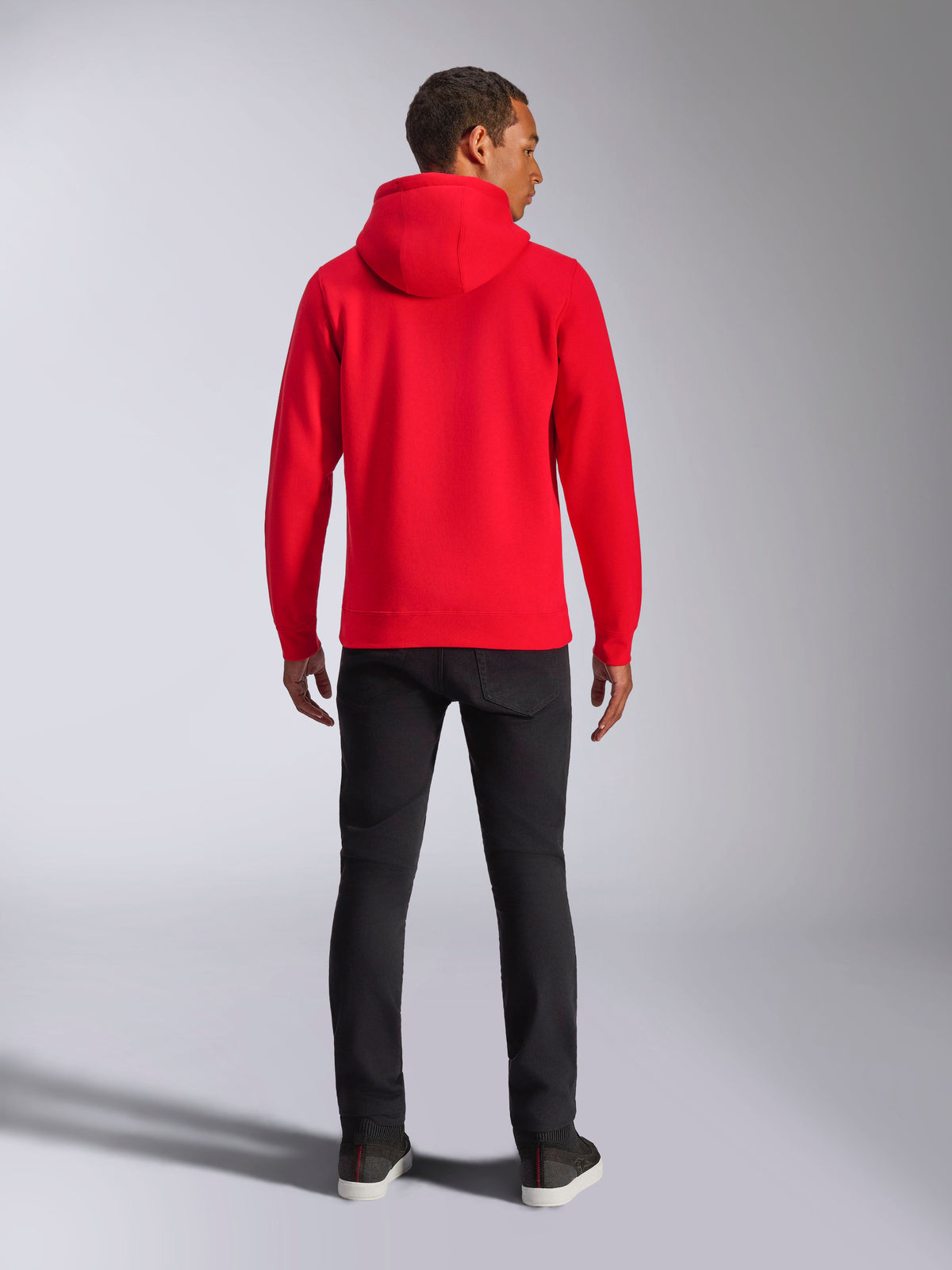 Alpinestars Ageless V3 Hoodie, Rückansicht, leuchtendes Rot, lässiger Streetwear-Pullover, getragen mit schwarzer Hose, modernes motorsport-inspiriertes Design