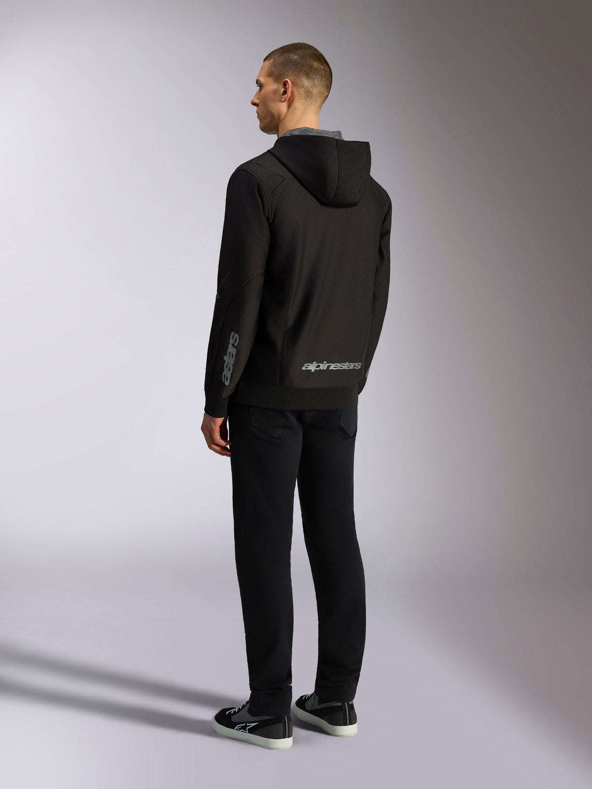 Alpinestars Sessions V3 Hoodie, lässige Motorsport-Streetwear, Schwarz mit grauer Wortmarke auf dem unteren Rücken und Unterarm, Poly-Fleece-Kapuzenjacke mit Reißverschluss und mesh-gefütterter Kapuze, Rückansicht am Modell, modernes sportliches Design