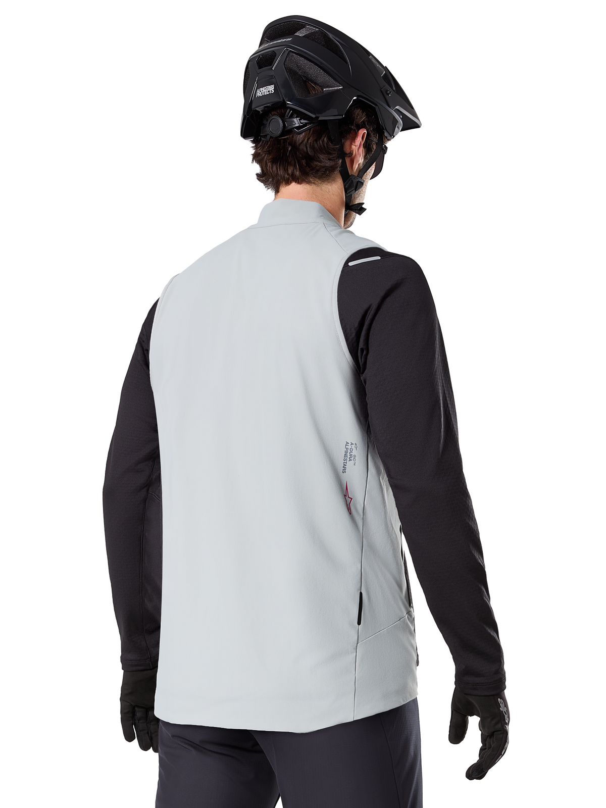 Alpinestars A-Dura Thermal Vest, Titanium Gray, rear view of model wearing a black long-sleeve jersey and MTB helmet, minimalist design with small red star logo on the back, lightweight insulated cycling gilet for off-road riding