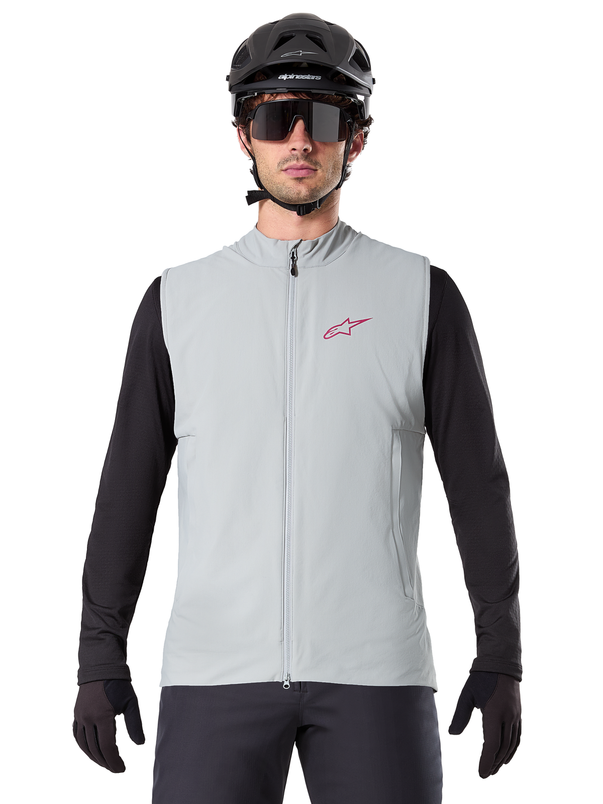Alpinestars A-Dura Thermal Vest, Cycling Gilet, Titanium Gray, worn with a black long-sleeve jersey and black cycling helmet, red Alpinestars star logo on chest, lightweight and insulated for mountain biking.