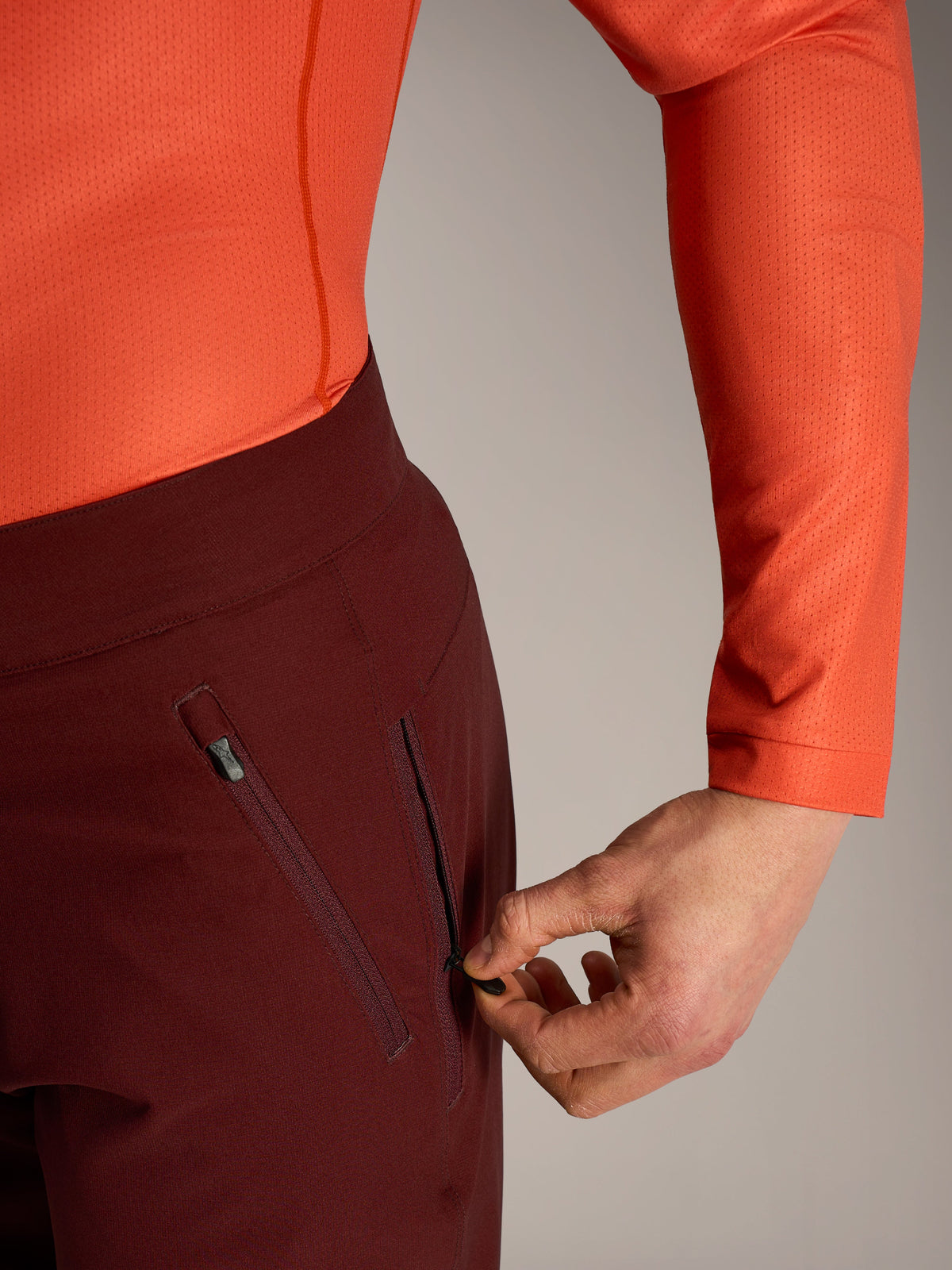 Alpinestars A-Dura Ride Shorts in Bordeaux, Hand beim Öffnen der mesh-gefütterten Reißverschlusstasche.