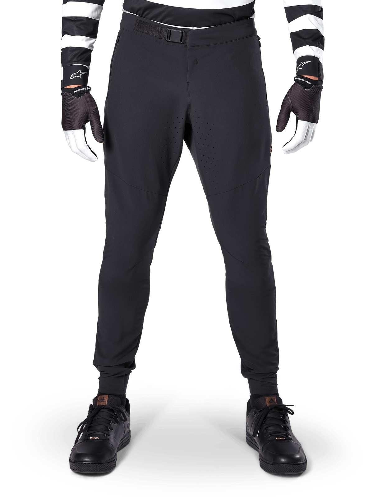 Alpinestars A-Aria Elite Pants, Mountain Bike Pants, Black, front view showing laser perforations and magnetic buckle closure, worn with a black and white striped jersey and black gloves, performance cycling gear for trail riding