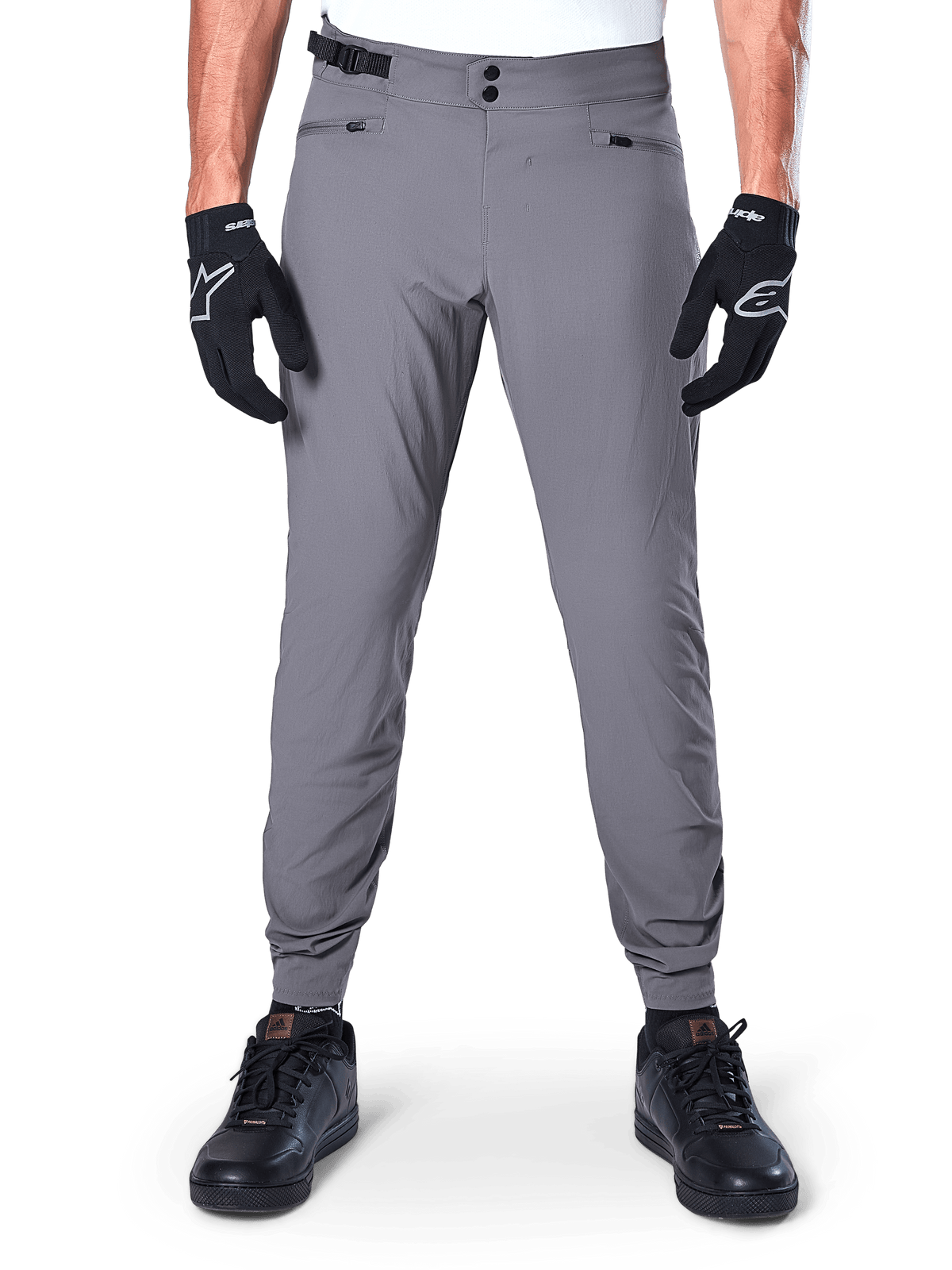 Alpinestars A-Dura Hose, dunkelgraue Mountainbike-Hose, Vorderansicht getragen mit schwarzen Handschuhen und schwarzen Sneakern, mit doppeltem Druckknopfverschluss, Reißverschlusstaschen und elastischen Bündchen, strapazierfähige Fahrradbekleidung für Trail-Riding