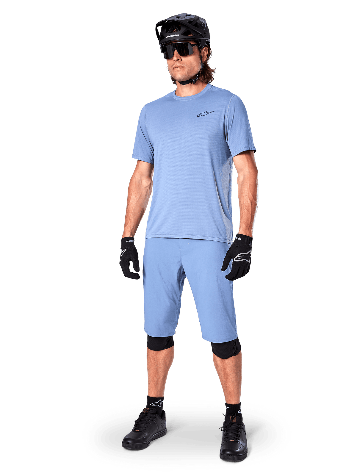 Model wearing Alpinestars A-Dura Shorts in Infinity Blue, matching light blue short-sleeve jersey, black MTB helmet, sunglasses, and black gloves, complete mountain biking outfit for trail riding