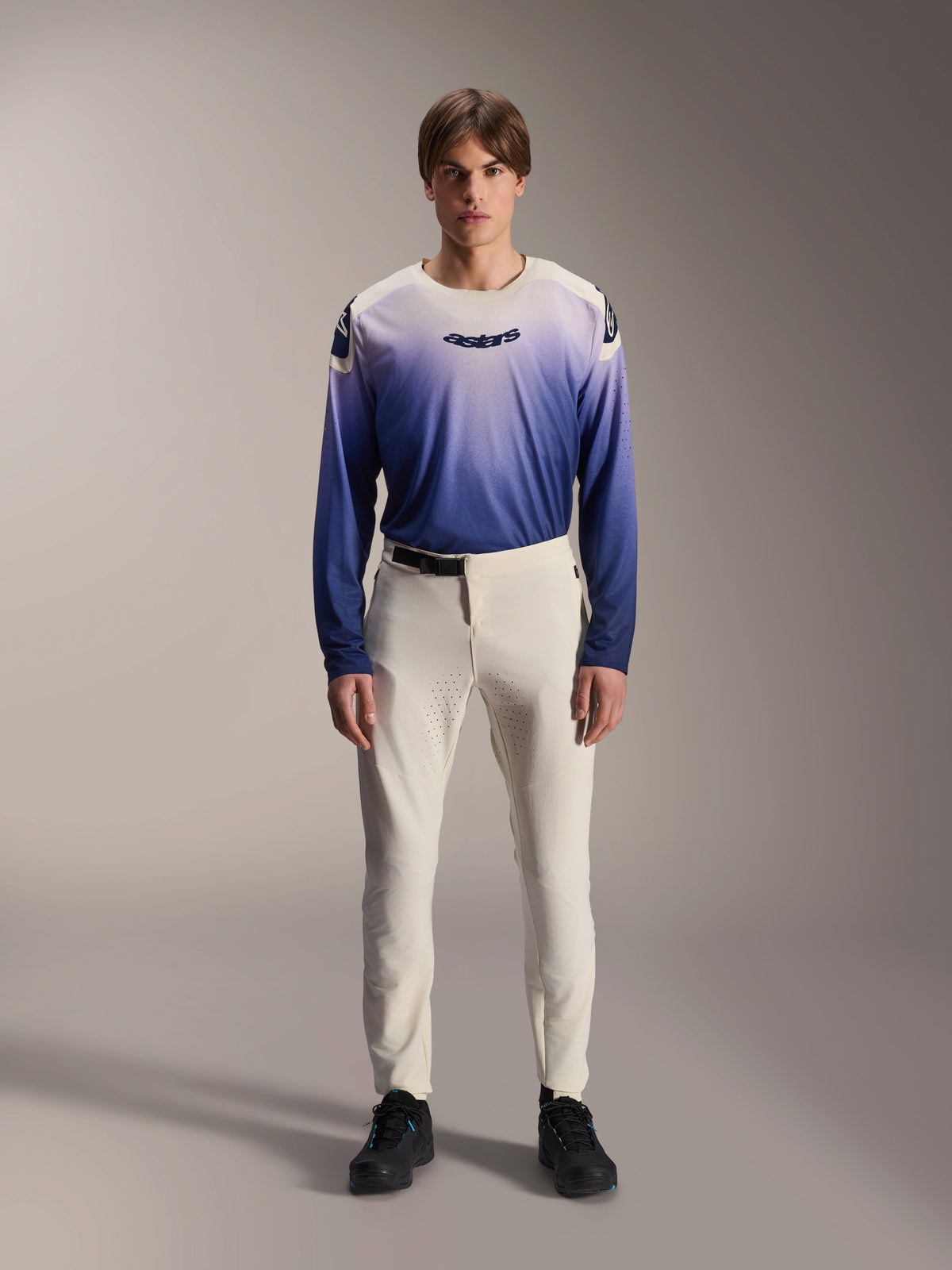 Alpinestars A-Aria Polartec Maker Elite Jersey, Long Sleeve Mountain Bike Jersey, Baja Blue and White gradient, featuring the astars logo on the chest, worn by a model with off-white pants and black shoes, performance cycling apparel